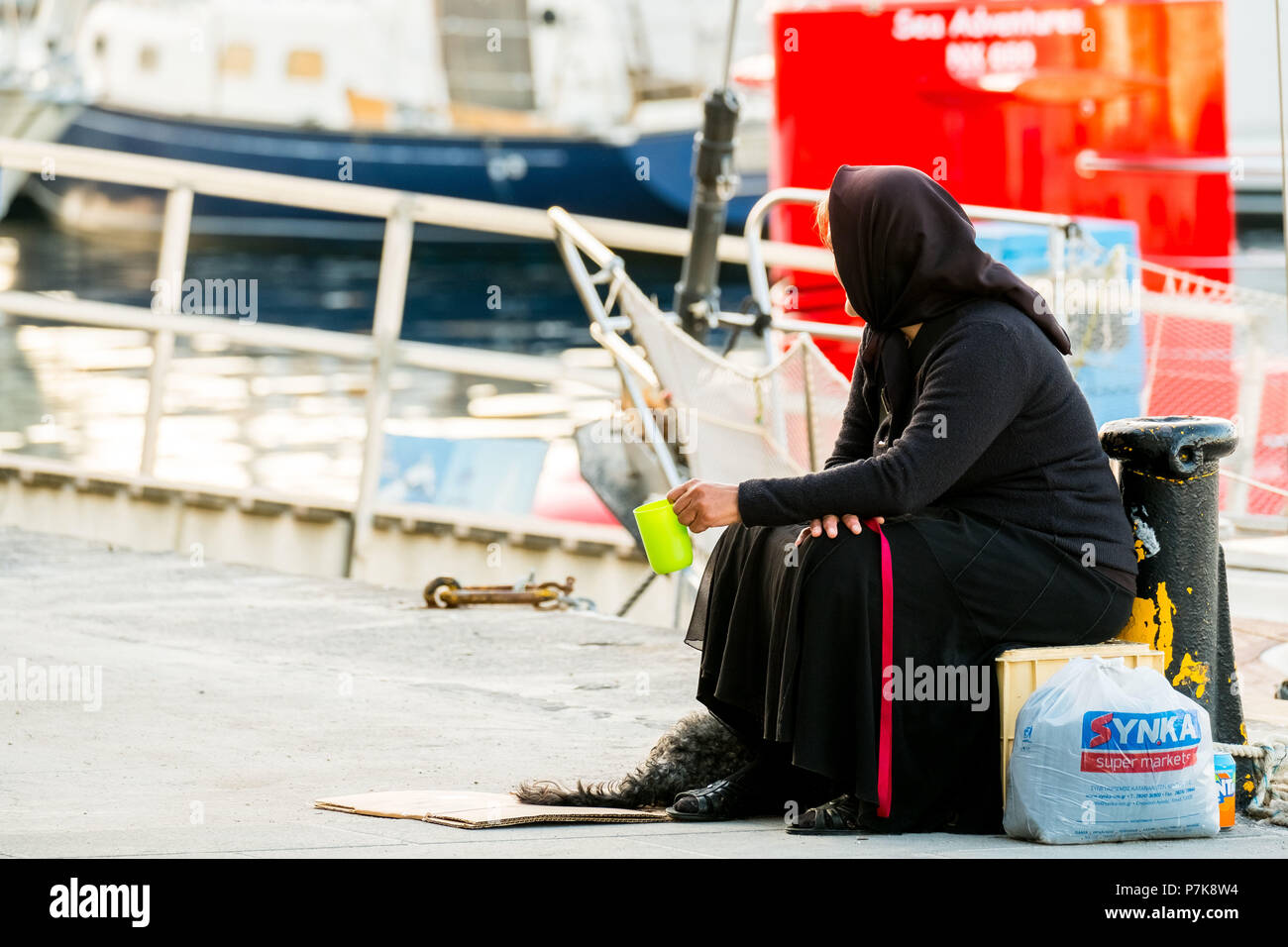 Woman begging in black robe in the port of Chania, poverty, Europe, Crete, Greece Stock Photo