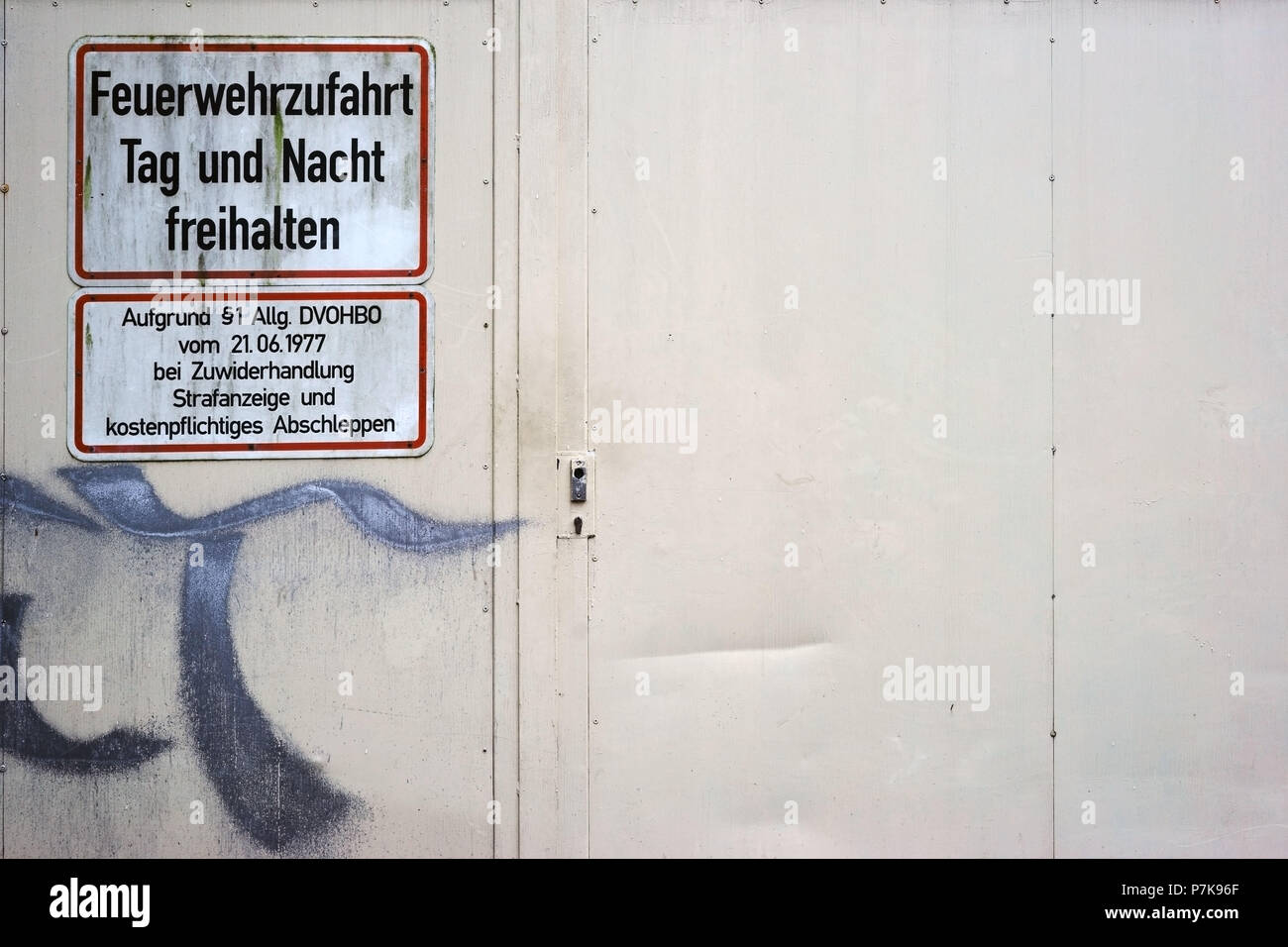 A scribbled fire-proof steel door of a shopping center with a warning sign 'Freihalten Feuerwehrzufahrt' Stock Photo