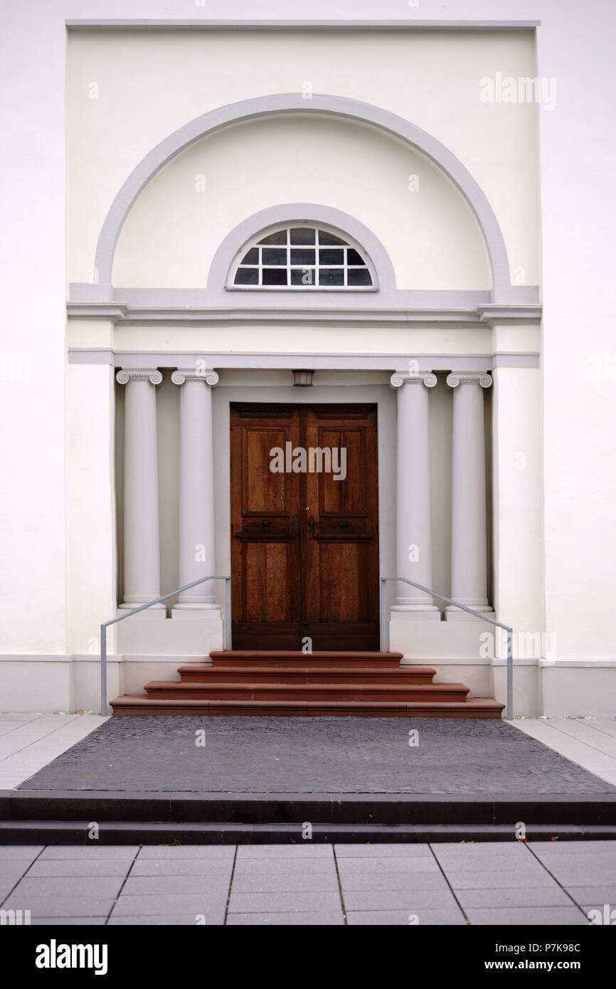 Entrance of a newly built and modern church with an entrance door with round arch and white walls Stock Photo