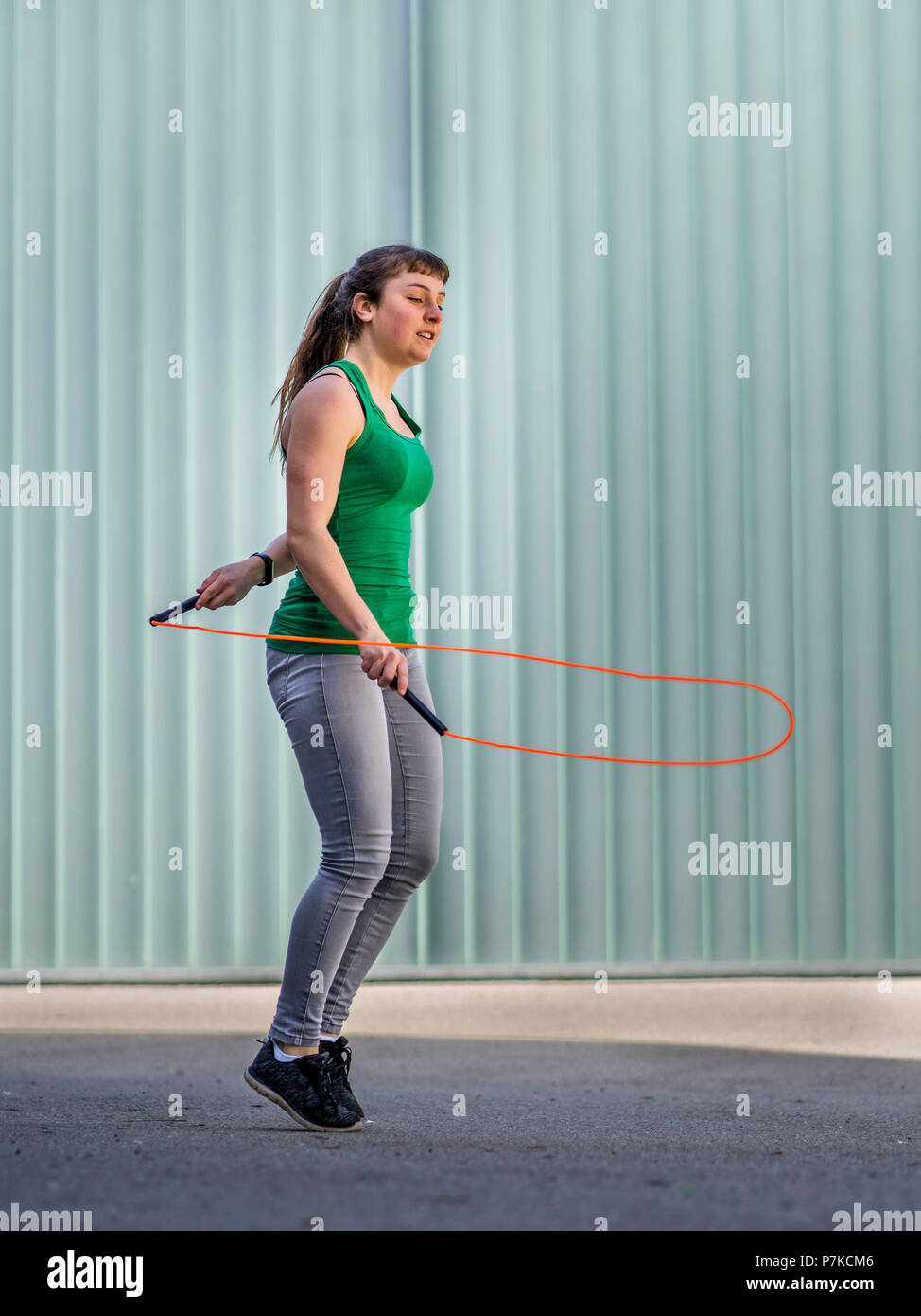 Teenager jumping rope, 18 years old, female, urban environment Stock Photo