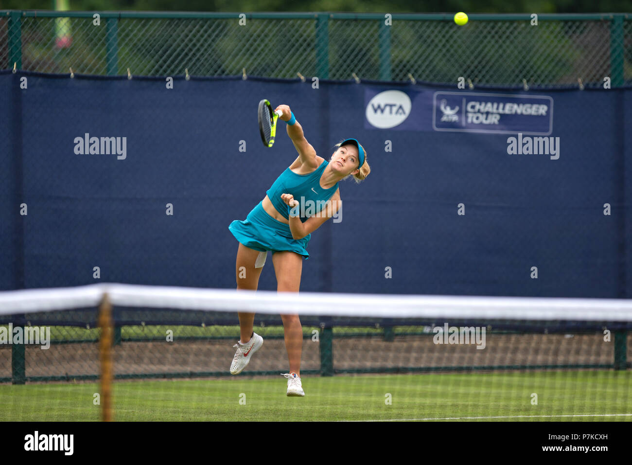 Katie Swan, professional British tennis player, in the middle of a serve during a match at the 2018 Nature Valley Open. Swan is pictured in the air with the ball, visible in shot, having left her racket. Stock Photo