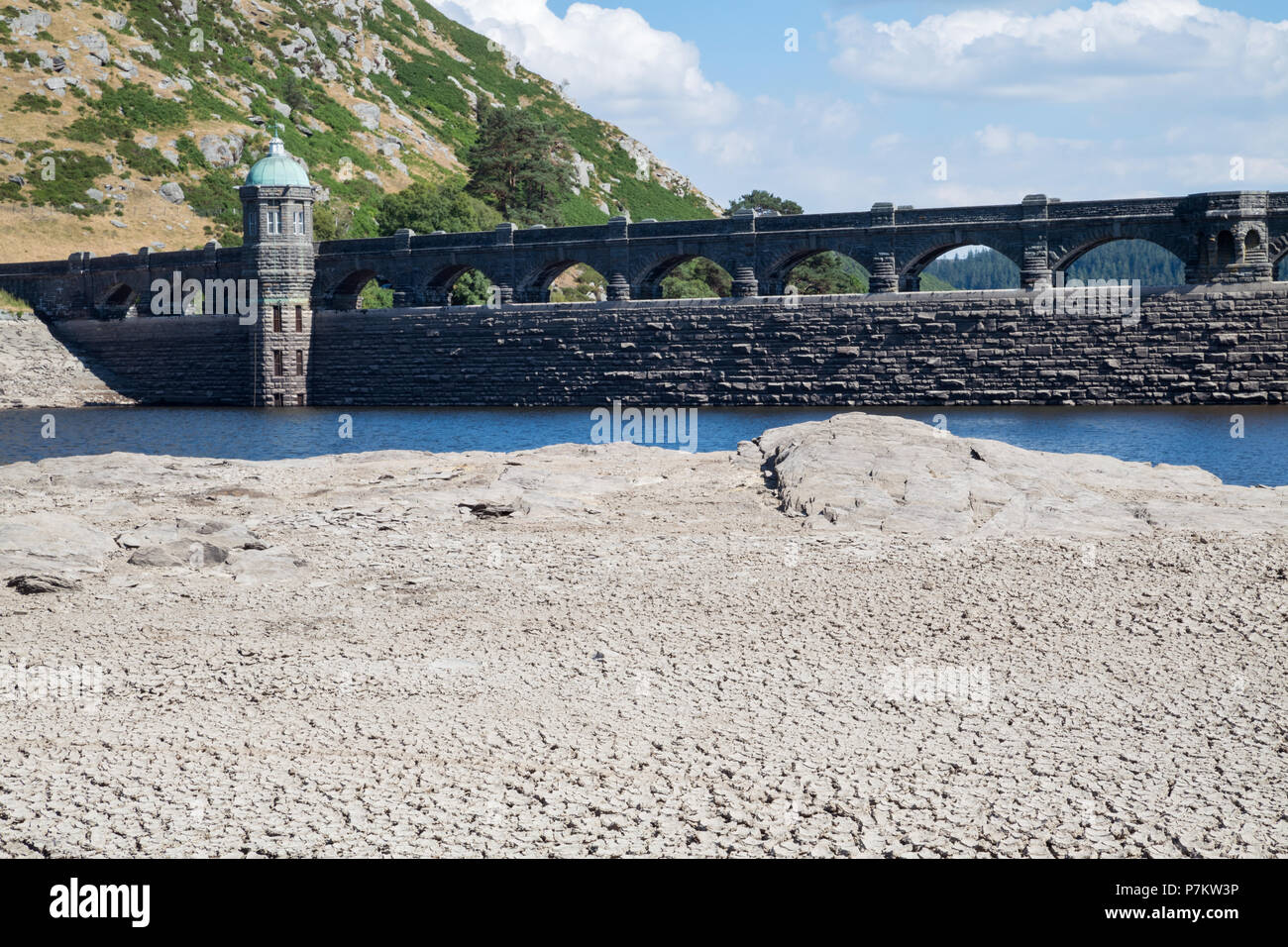 Craig Goch Dam, Wales, UK. 7th July 2018. Extremely low water levels revealing the shoreline due to the current hot weather in the UK, Normally water would be overflowing the arches generating electricity. The Dam normally when full has 2000 million gallons used to supply water to Birmingham along with other dams in the Elan valley. Stock Photo