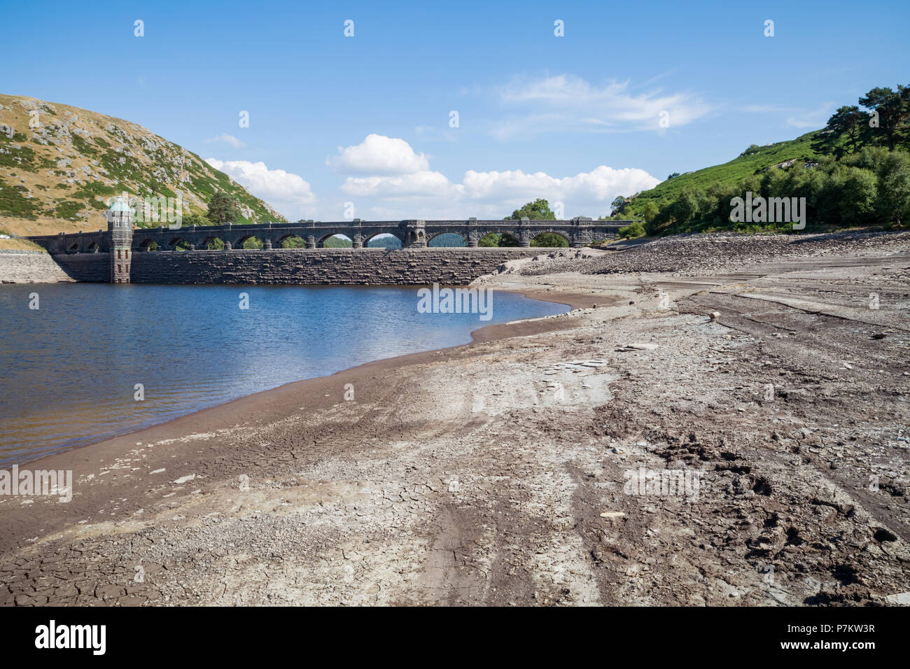 Craig Goch Dam, Wales, UK. 7th July 2018. Extremely low water levels revealing the shoreline due to the current hot weather in the UK, Normally water would be overflowing the arches generating electricity. The Dam normally when full has 2000 million gallons used to supply water to Birmingham along with other dams in the Elan valley. Stock Photo