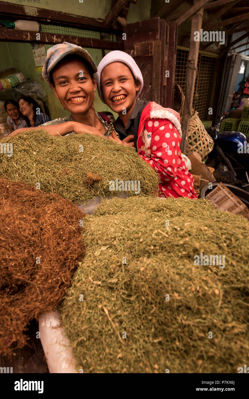 Two young women with typical betel nut mouth behind their tobacco at the market in Kutacane, Indonesia, Stock Photo