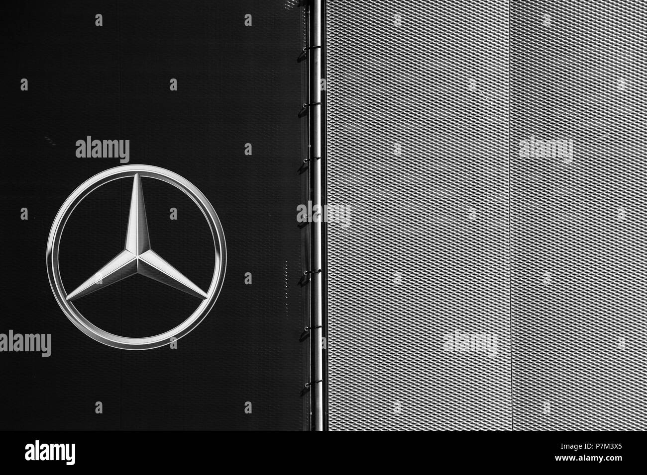 The symbol and the shiny star of Mercedes Benz on the modern facade of a car dealership. Stock Photo