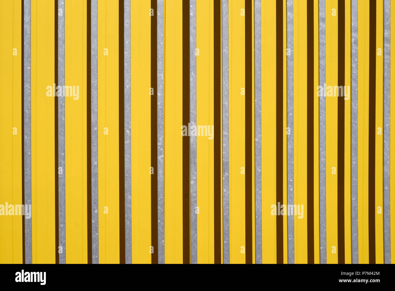 Side view of a color intensive corrugated iron wall of a shopping center with bars in front of the wall. Stock Photo