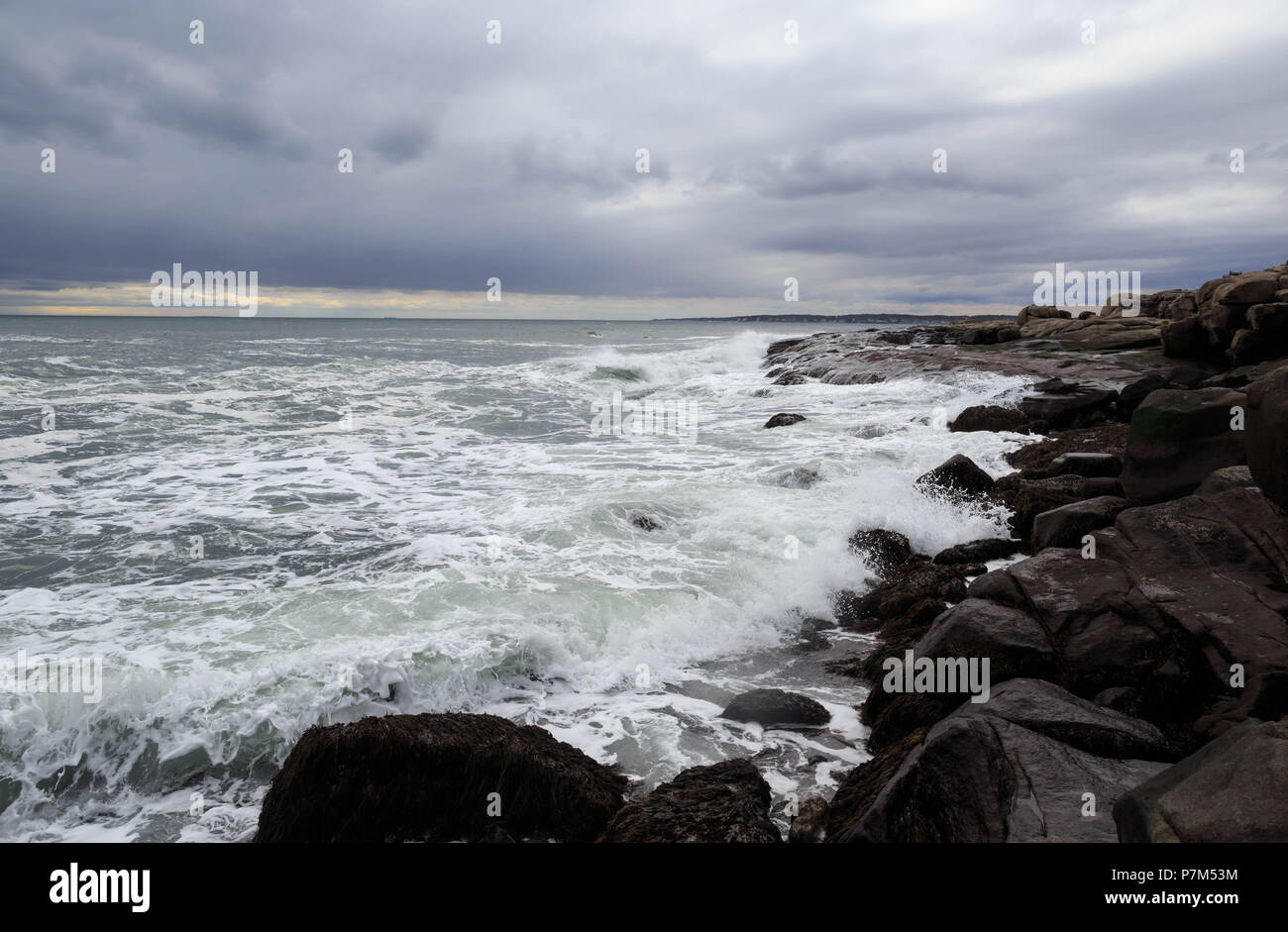 Small waves crash against rocky shore under dramatic storm clouds Stock ...