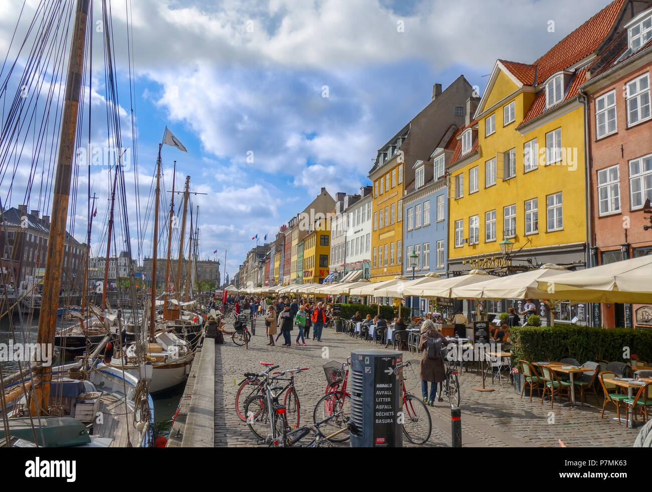 People stroll the cobblestone streets of Nyhavn area in Copenhagen Denmark Stock Photo