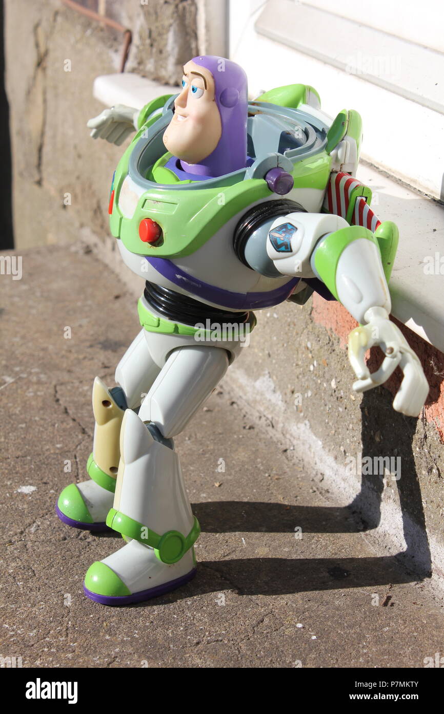 Buzz Lightyear Toy, Classic model on doorstep in sun casting a shadow, missing helmet Stock Photo