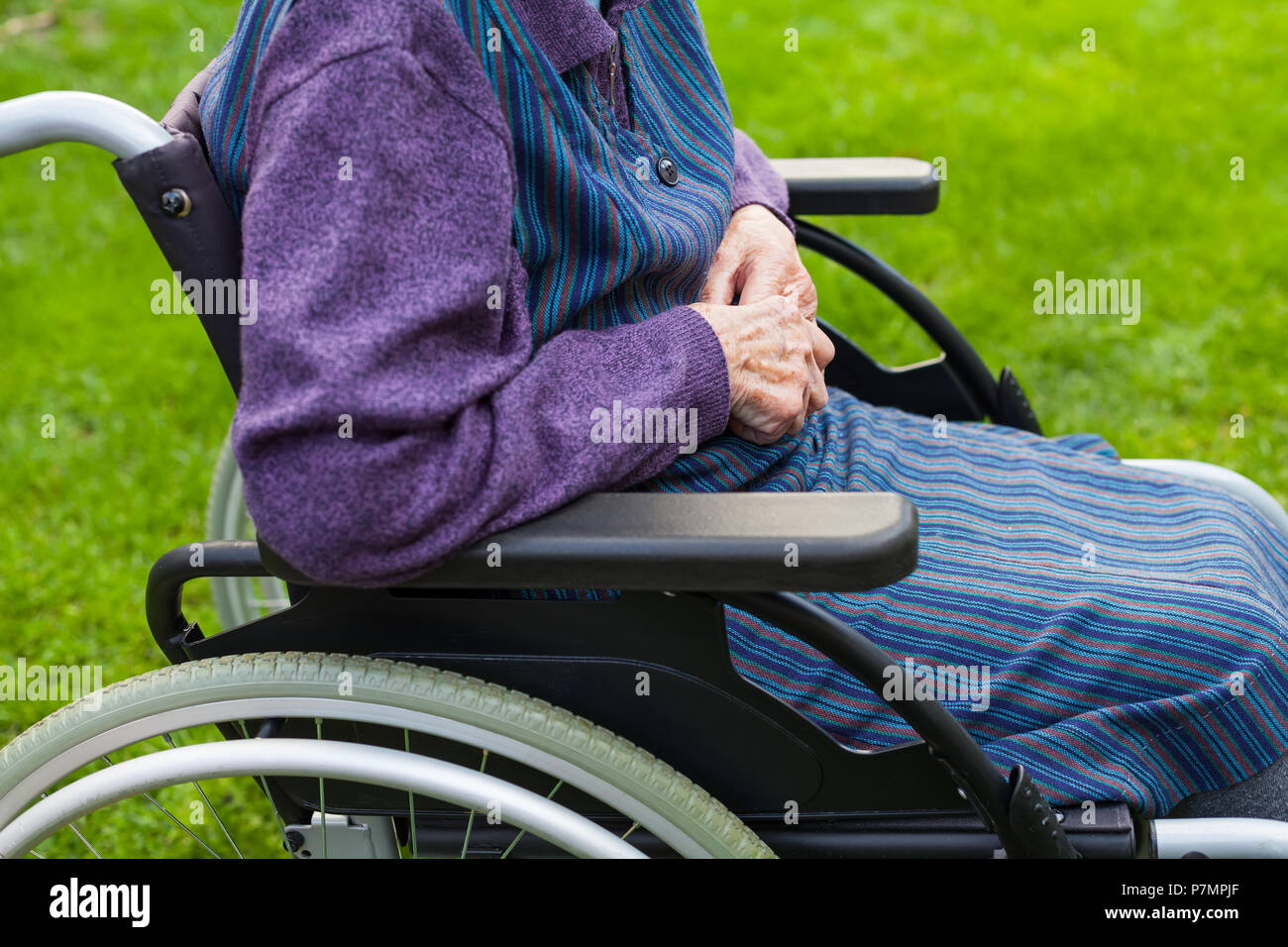 Old lady sitting in wheelchair suffering from dementia spending time