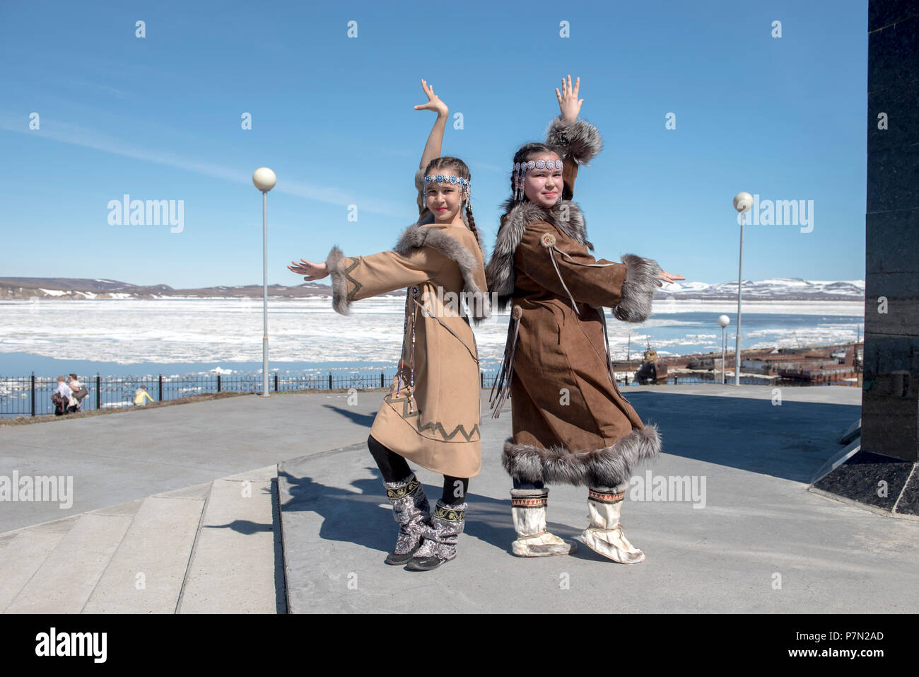 Two Chukchi girls in folk dresses against spring Arctic landscape Stock Photo