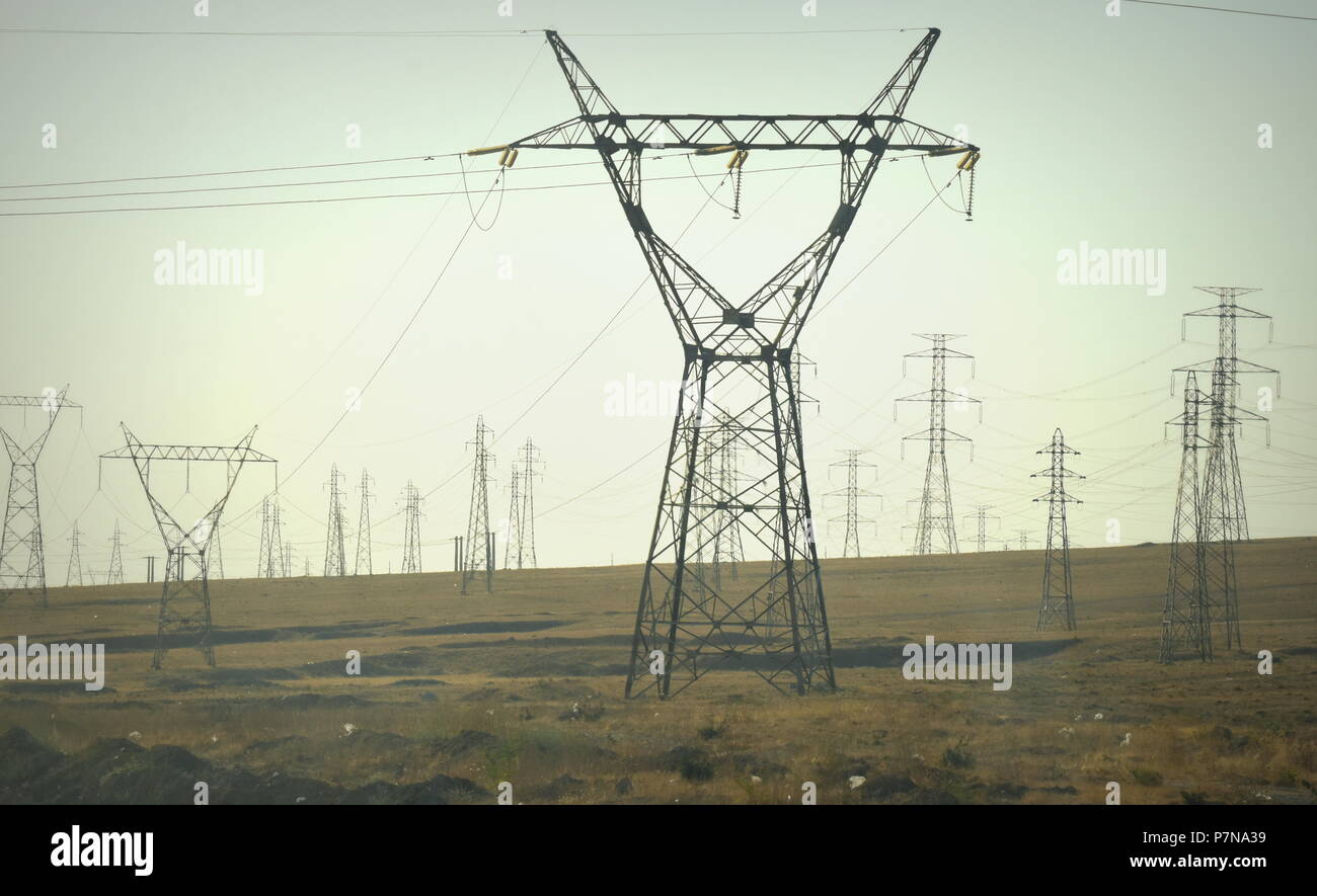Electrical power grid lines and sea of pylons distributing energy in a desert plain in Qazvin, Iran Stock Photo