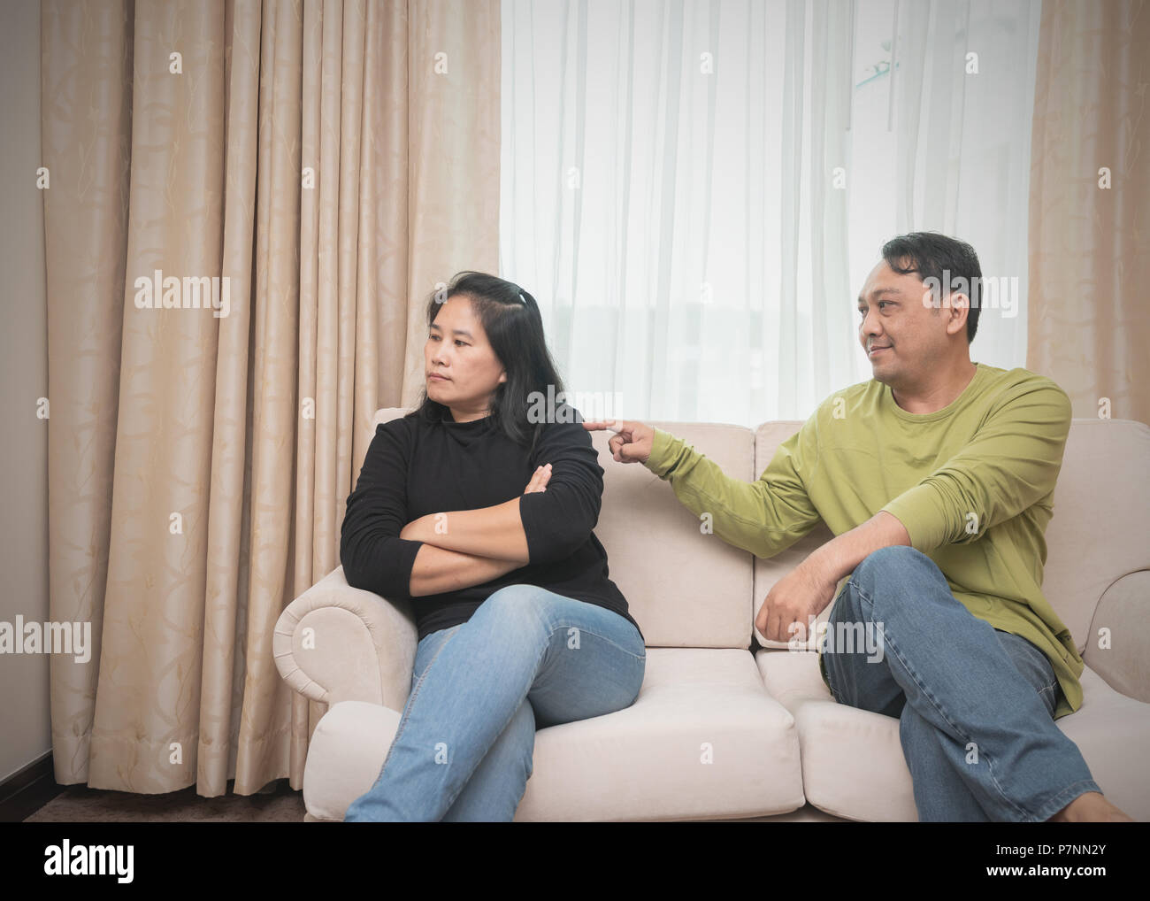 Couple relationship concepts. Husband trying to reconcile his wife after have an argument on sofa. Stock Photo
