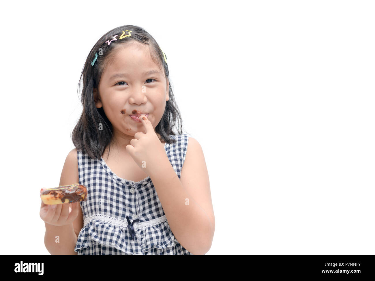 Little happy cute girl is eating donut isolated on white background. child is having fun with donut. Tasty food for kids. Funny time at home with swee Stock Photo