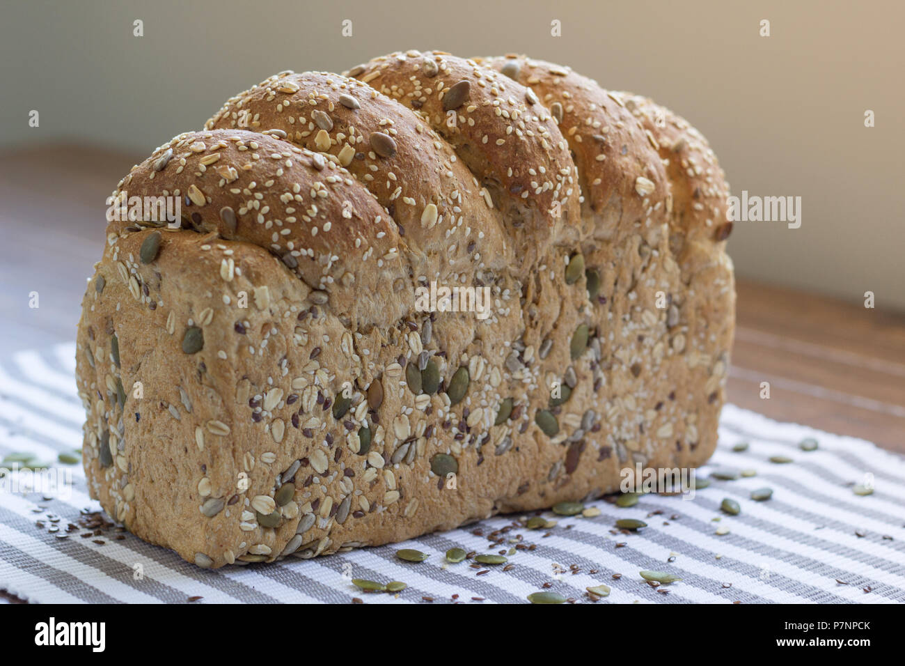 Single loaf of seeded multigrain bread sitting on striped cloth Stock Photo