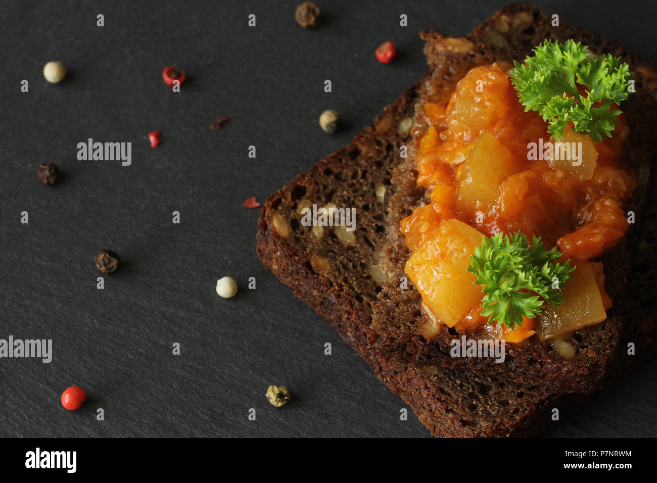 Canapes from a vegetarian ragout (stew) on a piece of bread on a black ...