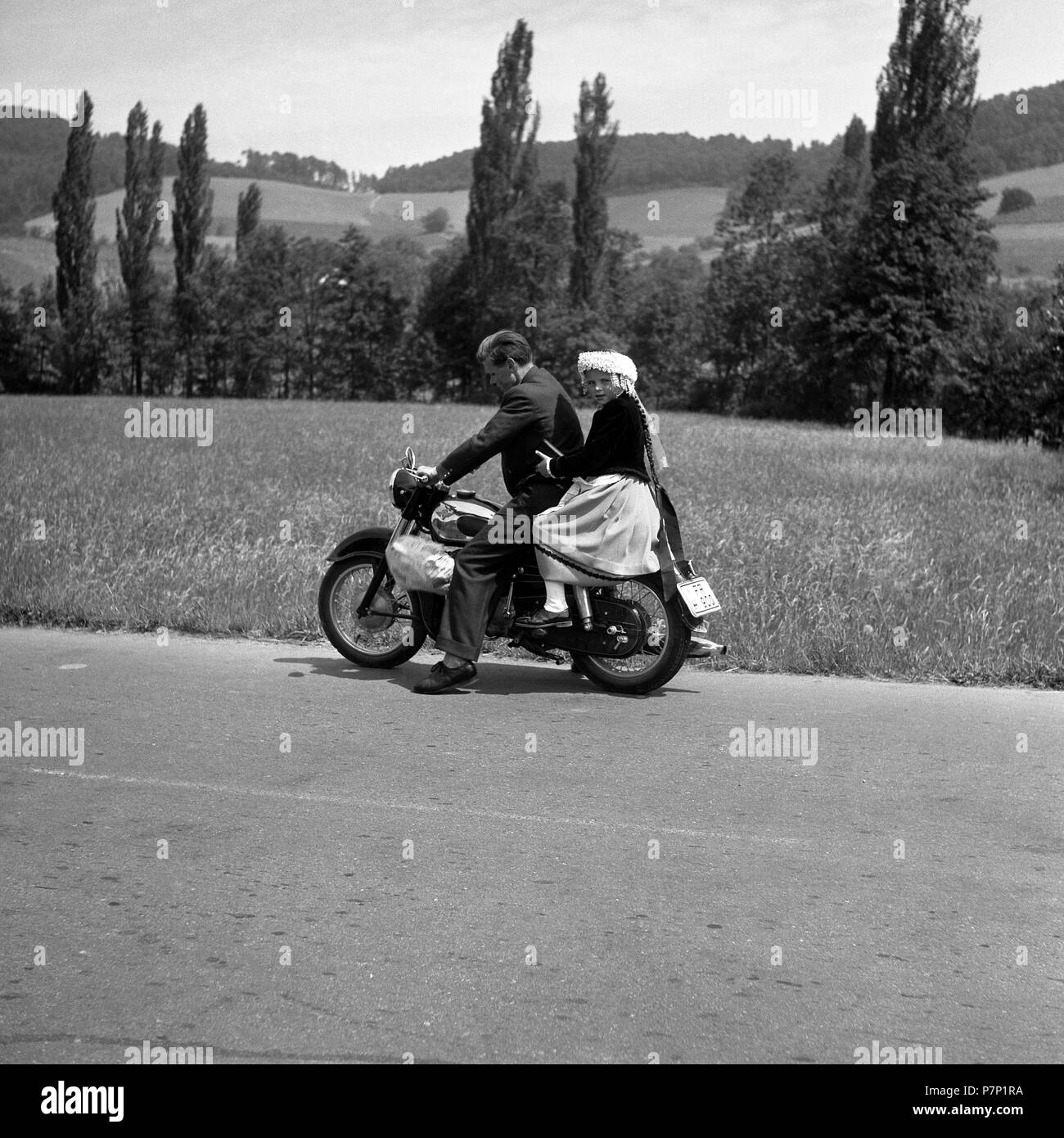 Man and daughter riding a motorbike on a country road, around 1950, near Freiburg, Germany Stock Photo