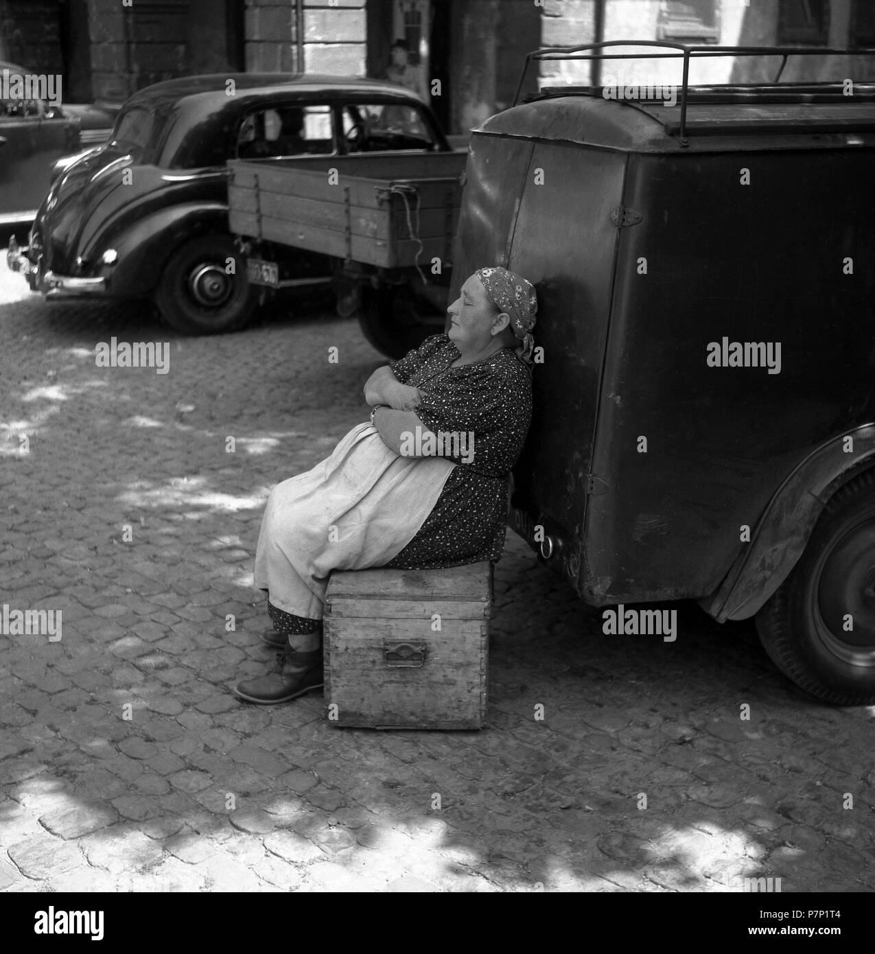 https://c8.alamy.com/comp/P7P1T4/woman-sitting-on-a-wooden-box-and-leaning-against-a-car-freiburger-mnstermarkt-ca-1945-to-1955-freiburg-germany-P7P1T4.jpg