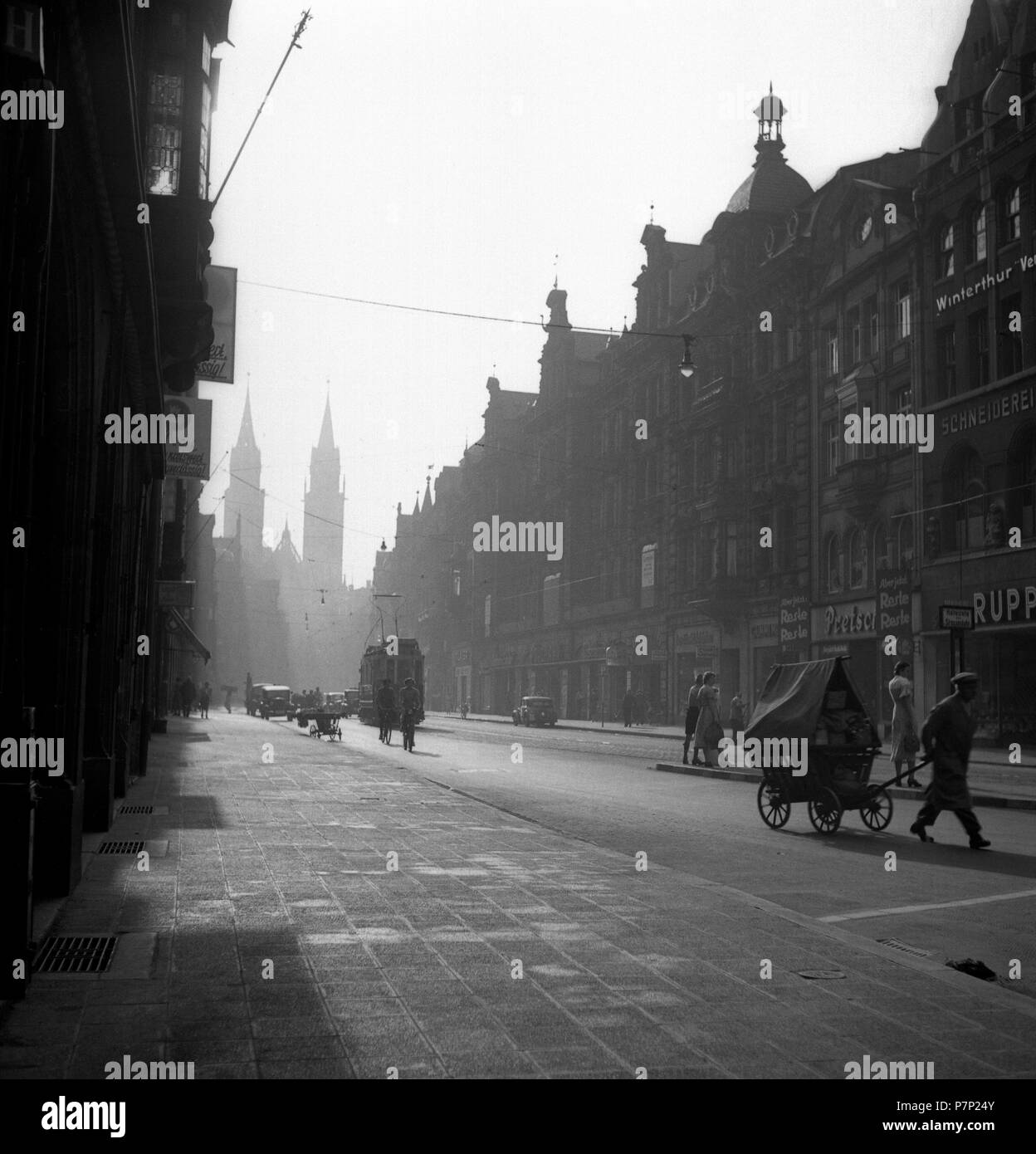 Street with cars, tram and a man with a cart, ca. 1945 to 1955, Freiburg, Germany Stock Photo