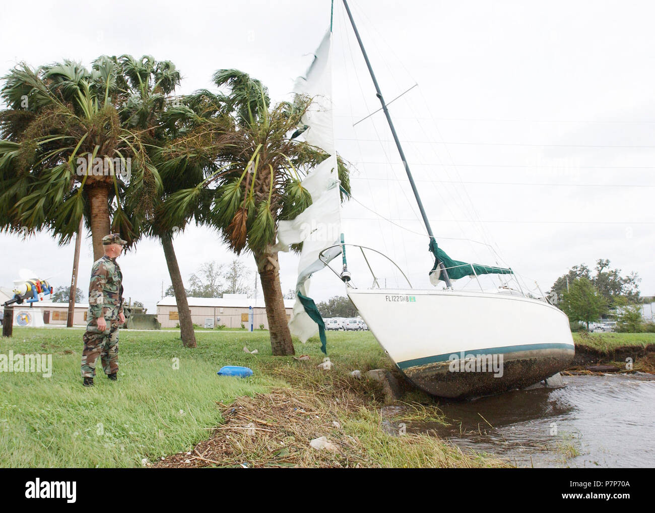 Hurricane Relief-17. US Navy (USN) Builder (BU2) James A. Wallace, assigned to Naval Construction Battalion Unit Four One Zero (CBU-410), assesses damage to a sailboat blown ashore after Hurricane Jeanne. Stock Photo