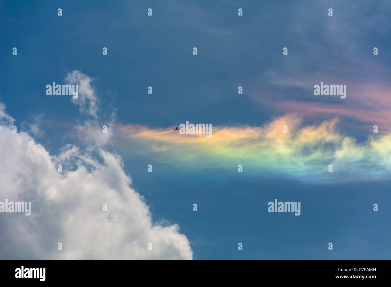 Cirrus rainbow cloud with spectral colors. Cessna passing by. Stock Photo