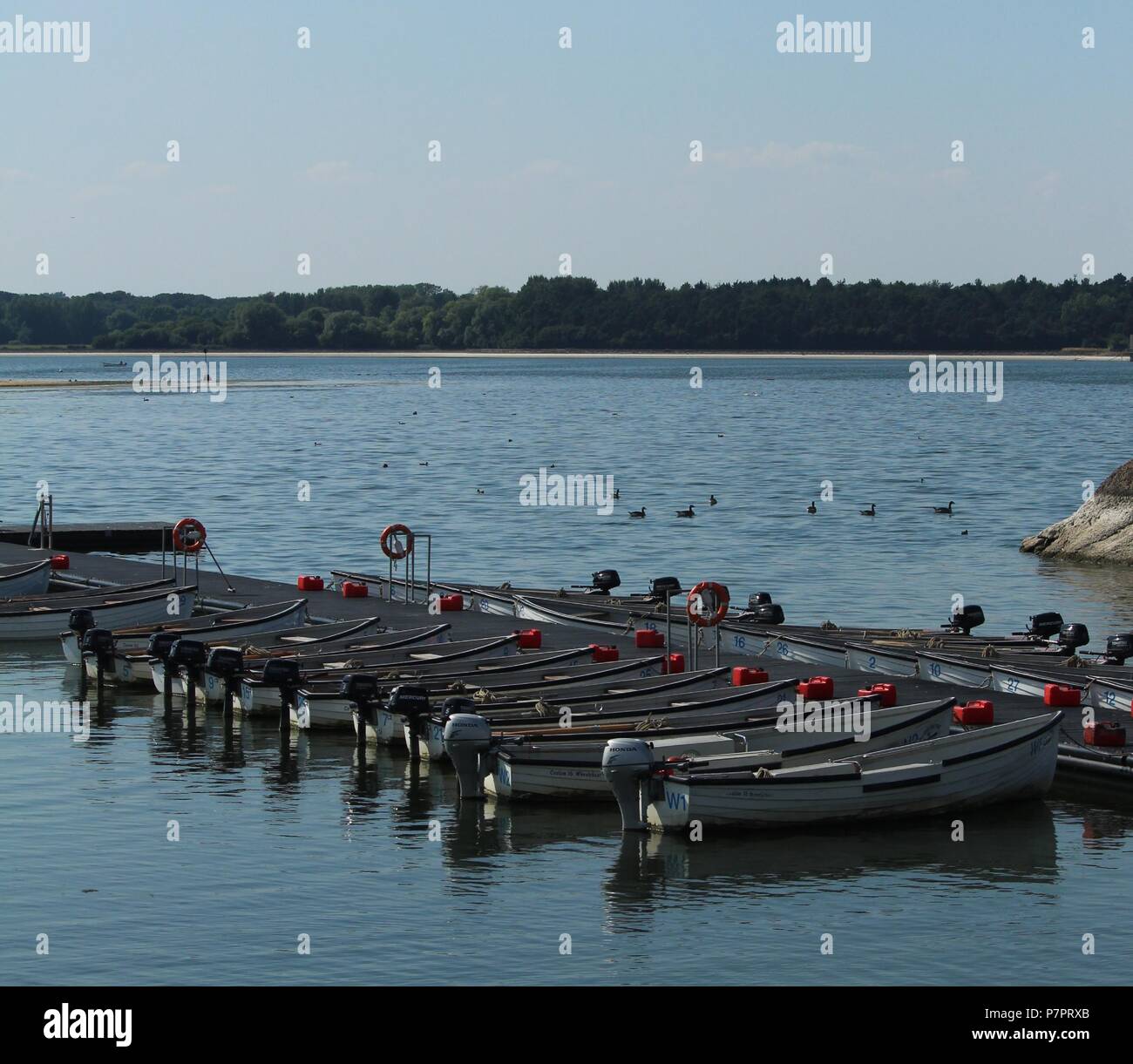 Waterfront scene - A Line of fishing boats moored on the water on a late afternoon at Hanningfield Reservoir, Essex, Britain. Stock Photo
