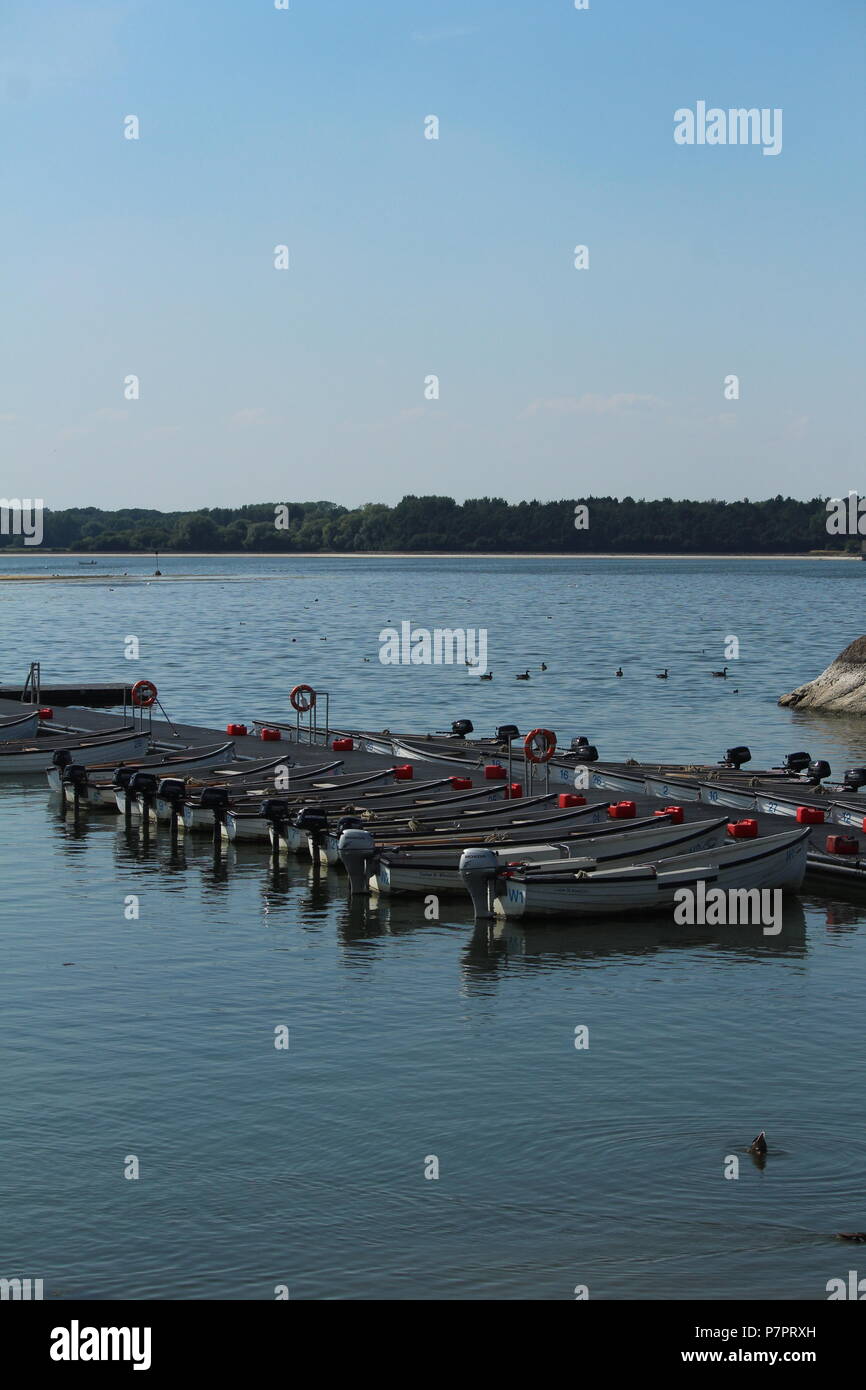 Waterfront scene - Portrait shot of a Line of fishing boats moored on the water on a late afternoon at Hanningfield Reservoir, Essex, Britain. Stock Photo