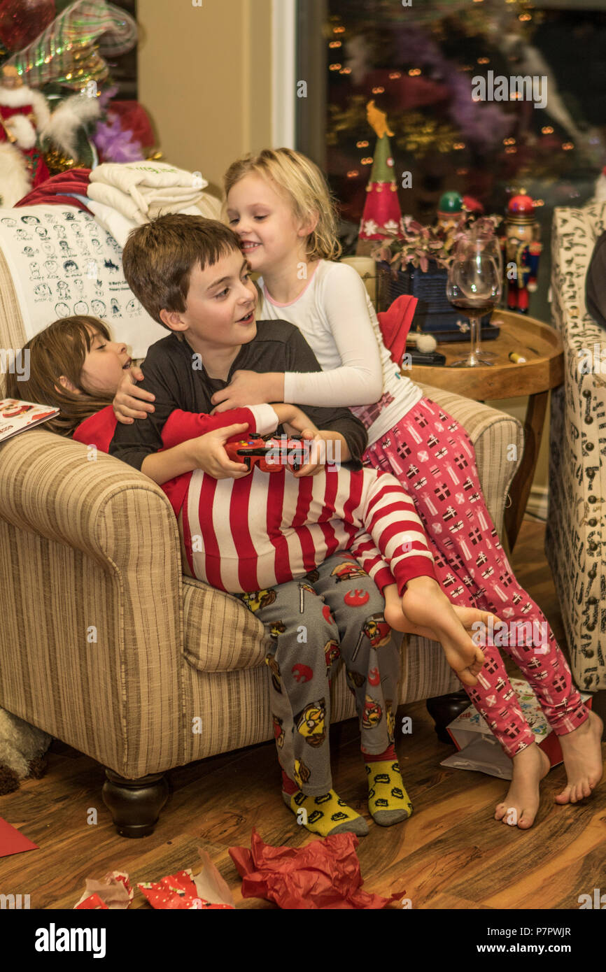 Sister And Cousin Sitting In Chair Hugging Brother In Front Of