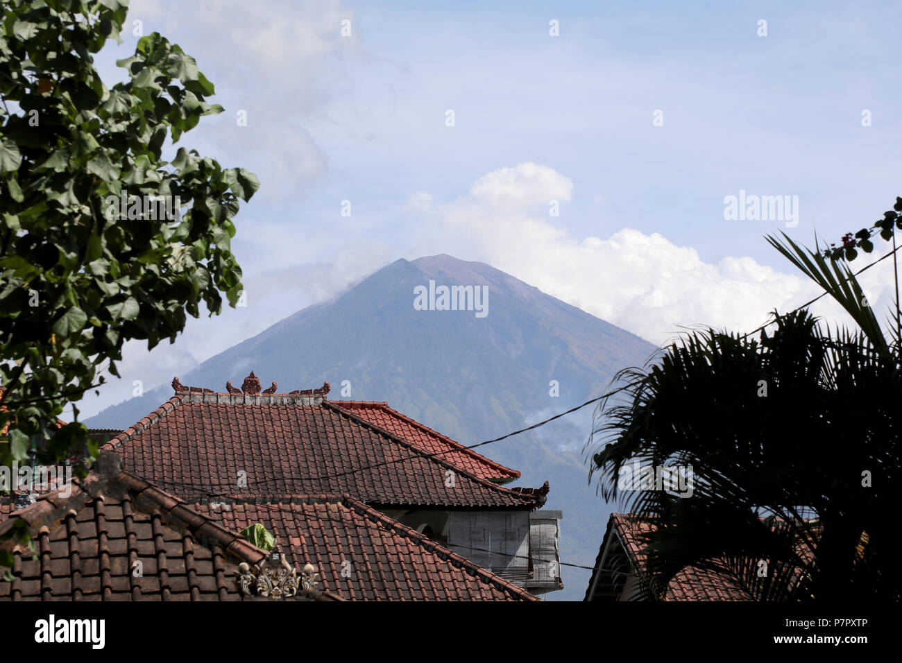 Amed, Indonesia – July 3 2018: The volcano of Mount Agung rises above the rooftops of a village in east Bali, Indonesia Stock Photo