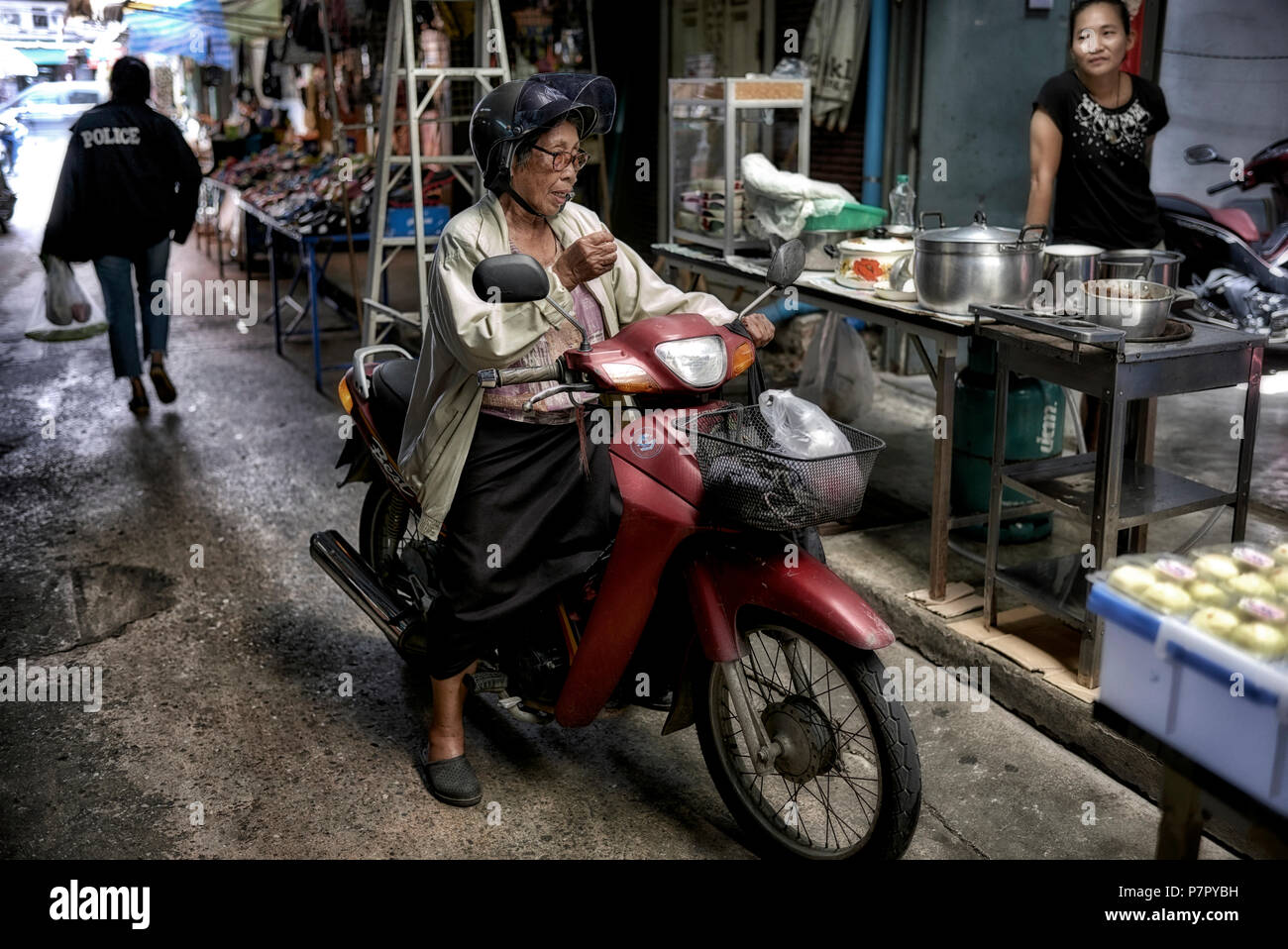 Senior woman riding a motorcycle Thailand street scene Stock Photo