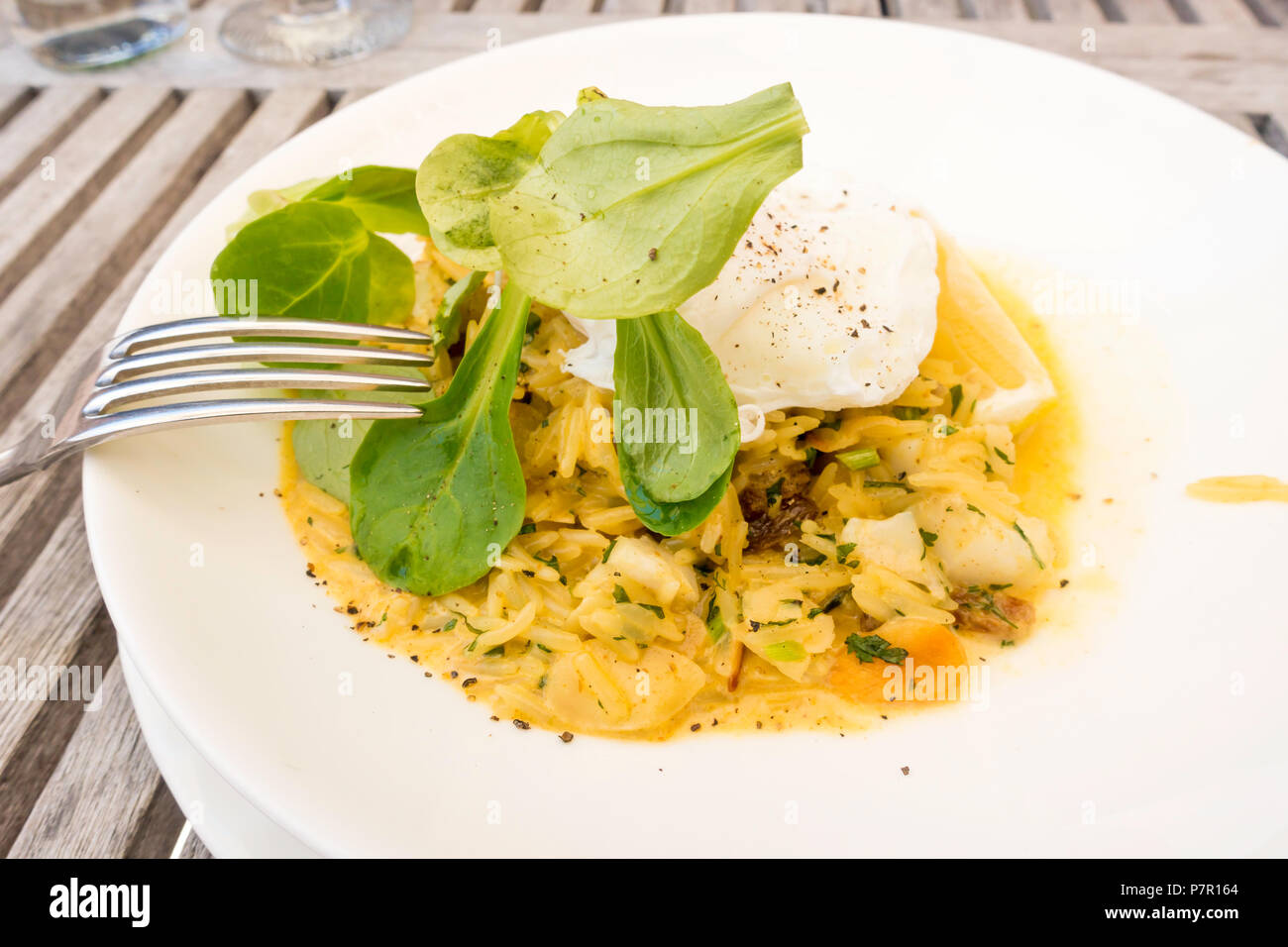 Kedgeree a breakfast dish that originated in India curried rice smoked haddock egg raisins with a poached egg on top Stock Photo