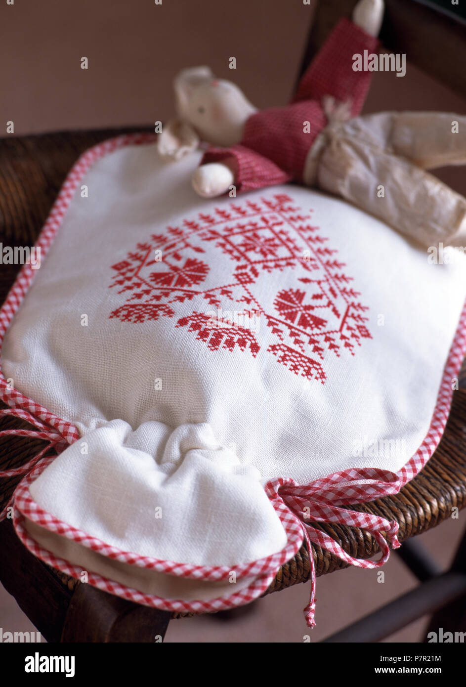 Close-up of a white hot water bottle cover with red cross stitch decoration Stock Photo