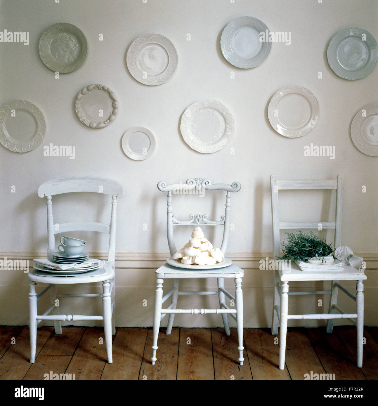 Collection Of White Plates On Wall Above Three White Painted