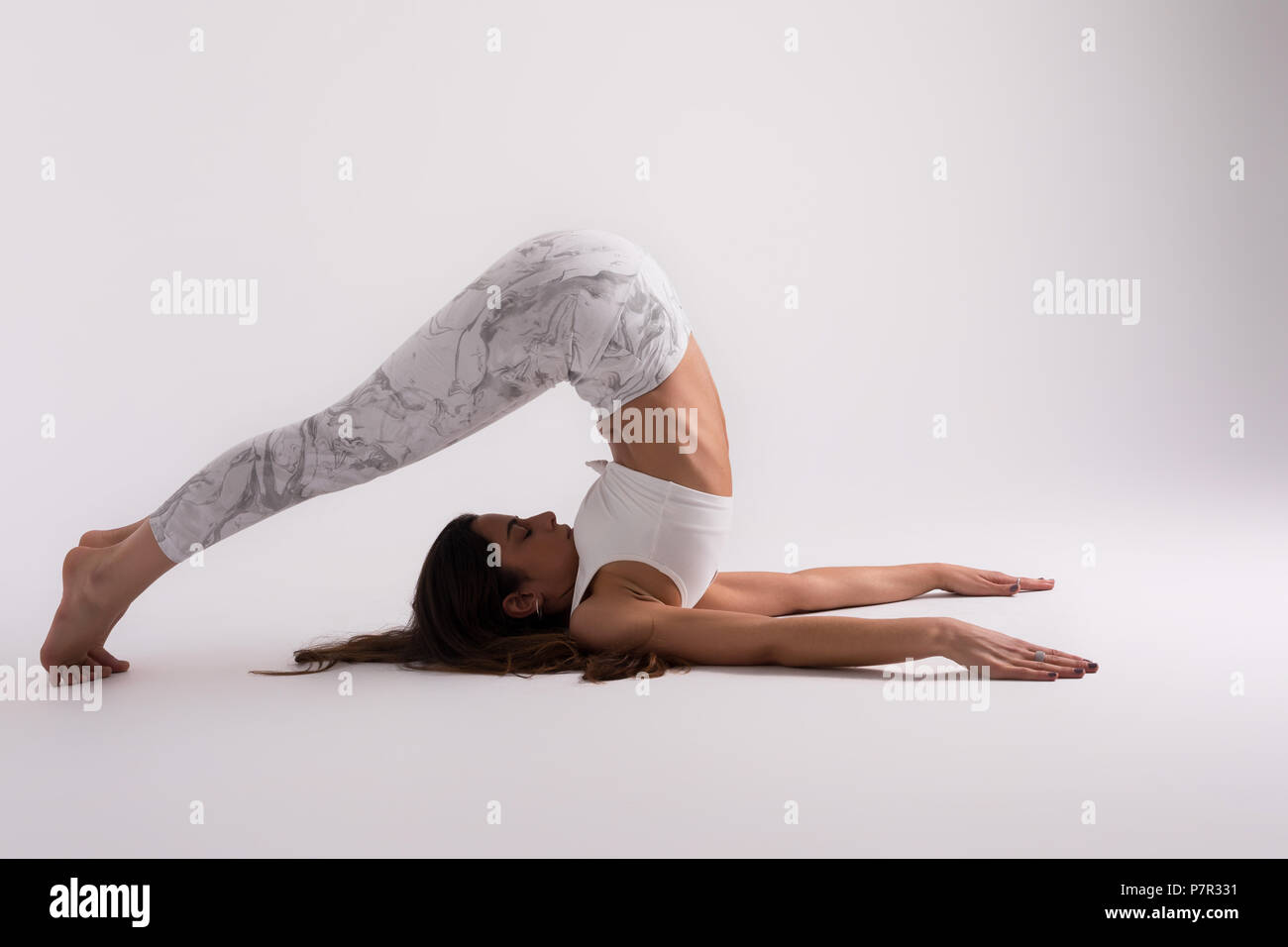 Sporty young woman doing yoga practice isolated on white background ...