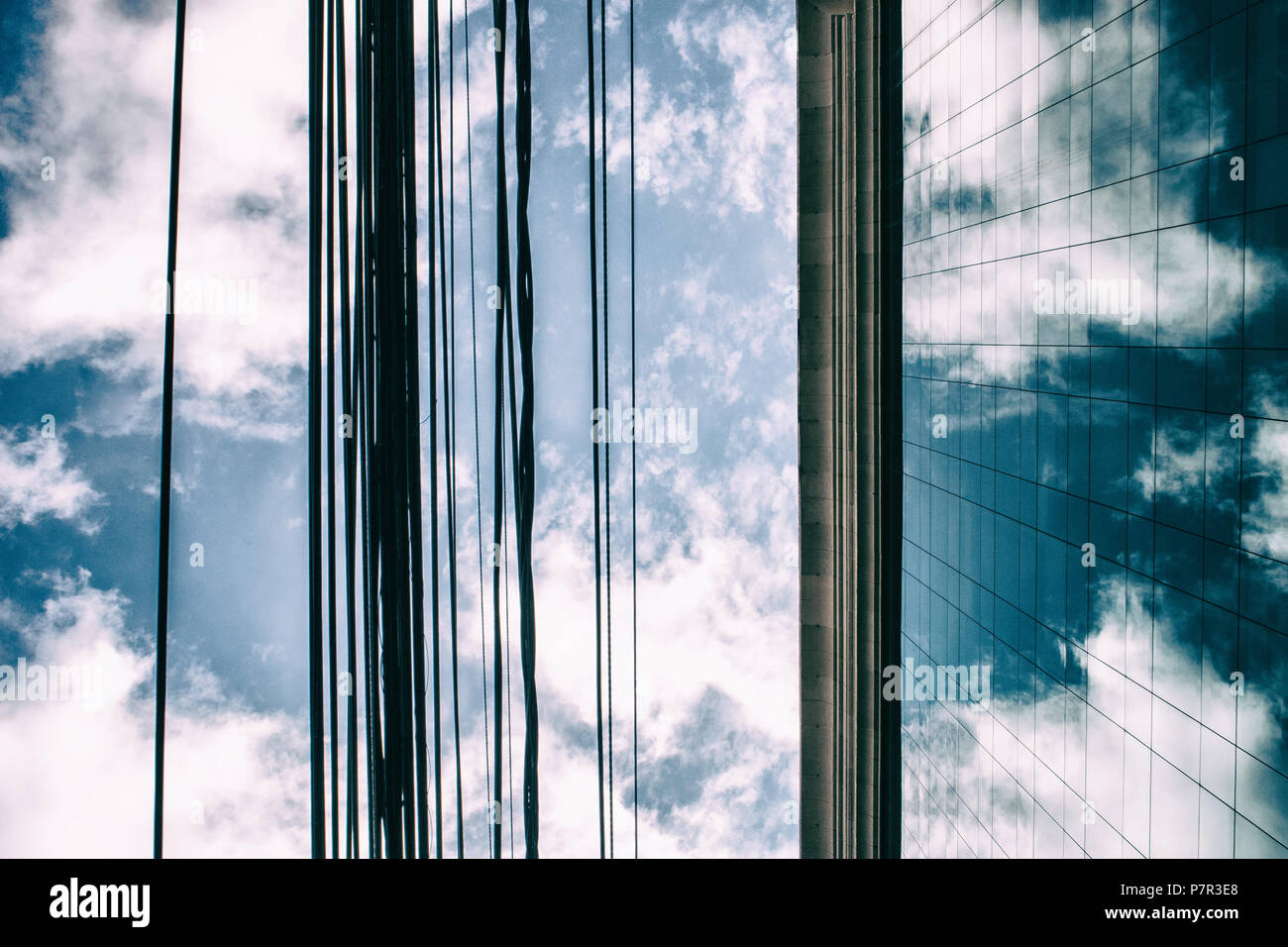 Clouds in a blue sky reflected in glass windows of an office building ...