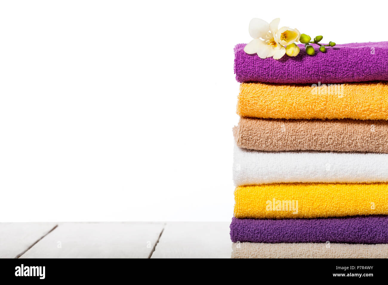 Stack of bath towels on light wooden table and white background closeup Stock Photo
