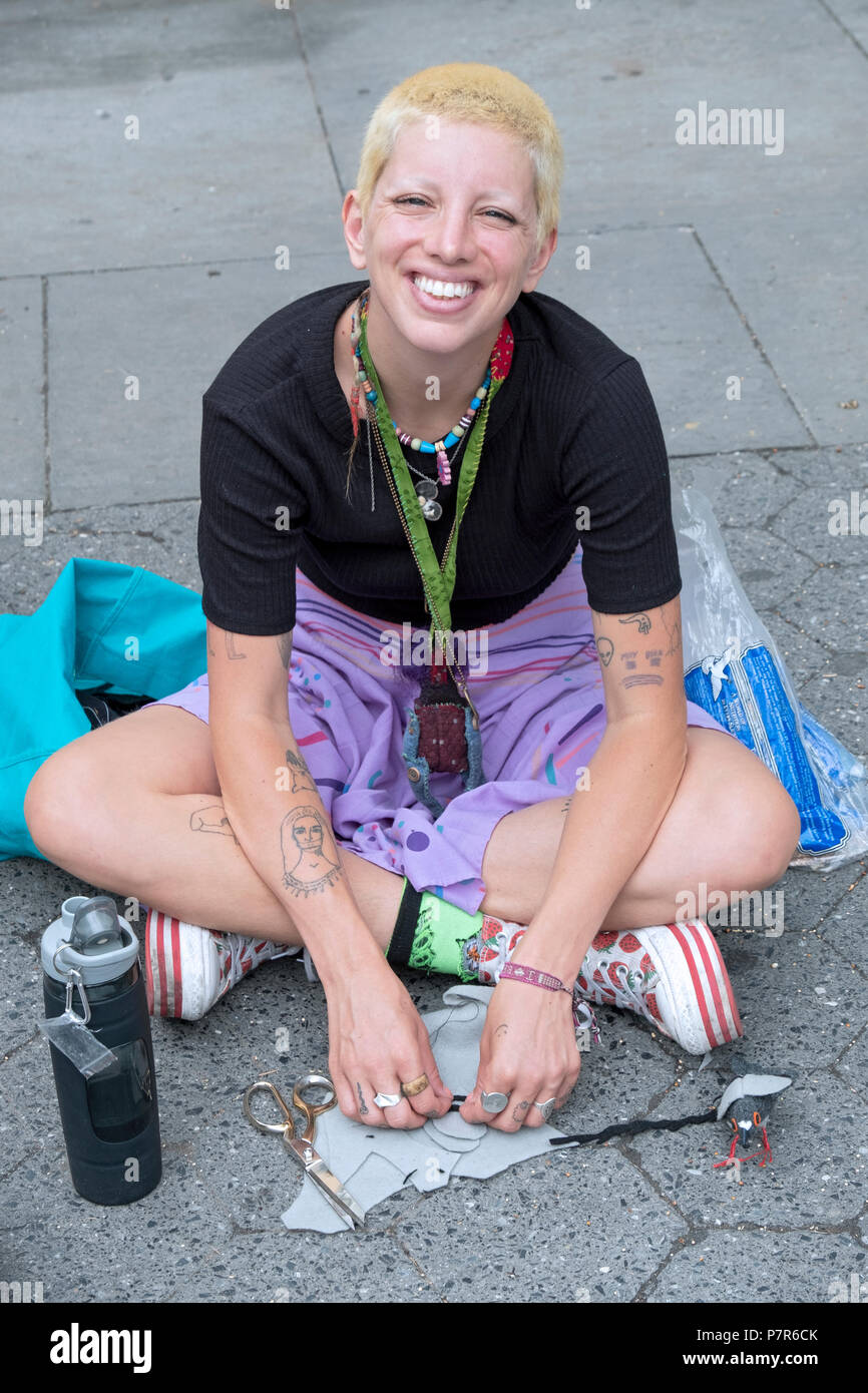 Posed portrait of a pretty young lady with short blond hair & several small tattoos. In Union Square Park in New York City. Stock Photo
