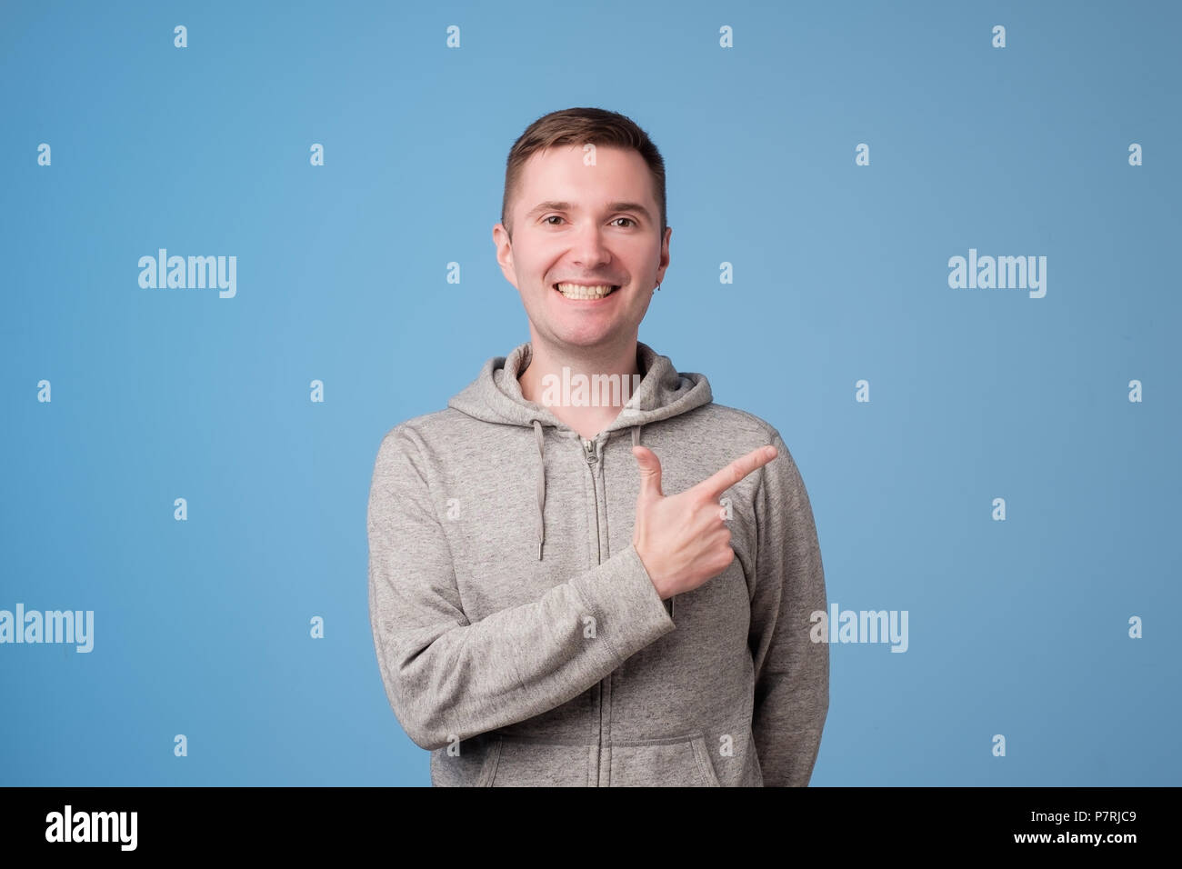 Cheerful handsome man showing direction and pointing with finger Stock Photo