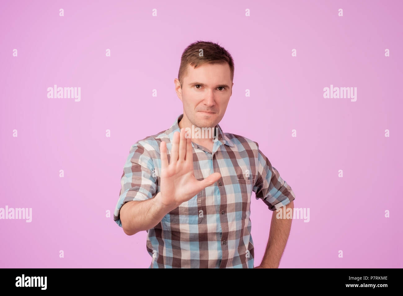 Portrait of european serious young man stretching hand towards camera with stop or hold gesture Stock Photo