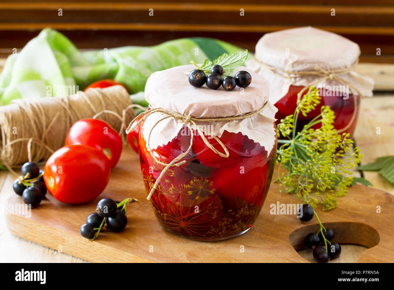 Marinated tomatoes. Pickles tomatoes with black currant on the kitchen table in a rustic style. Stock Photo
