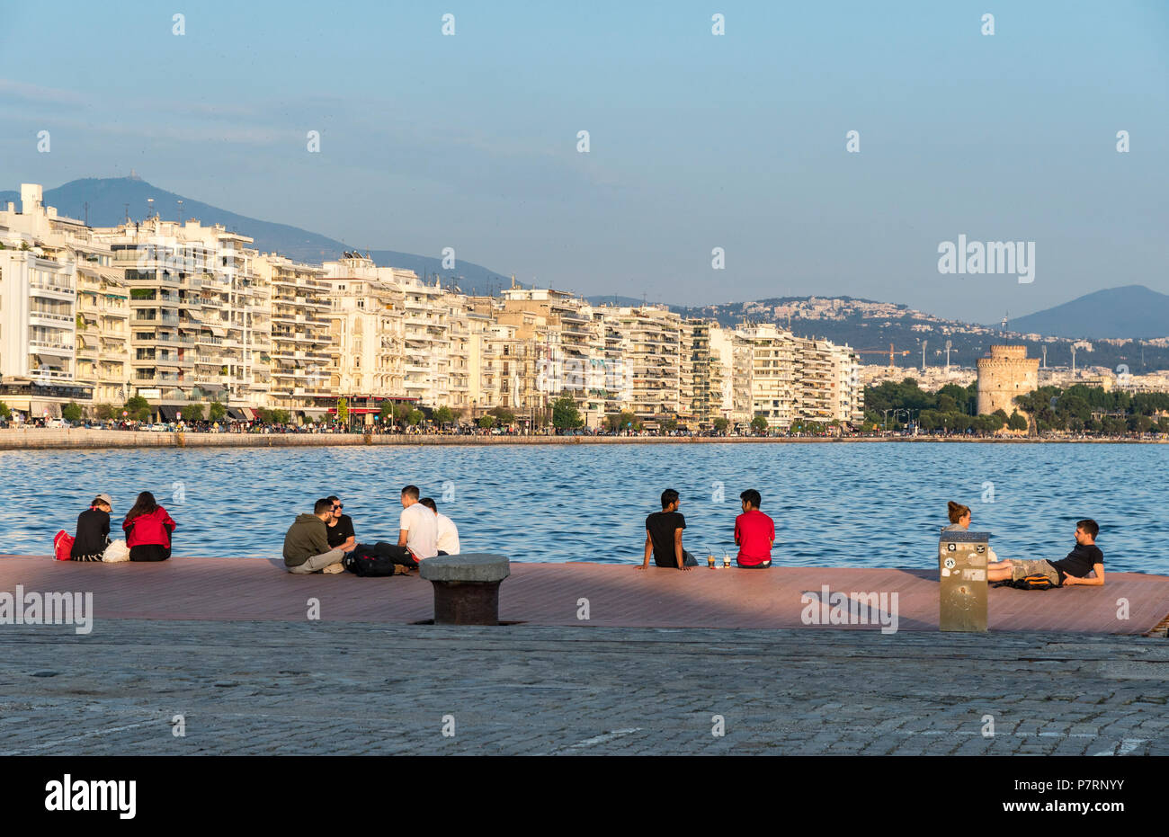 People relaxing on Thessaloniki waterfront with apartment blocks on