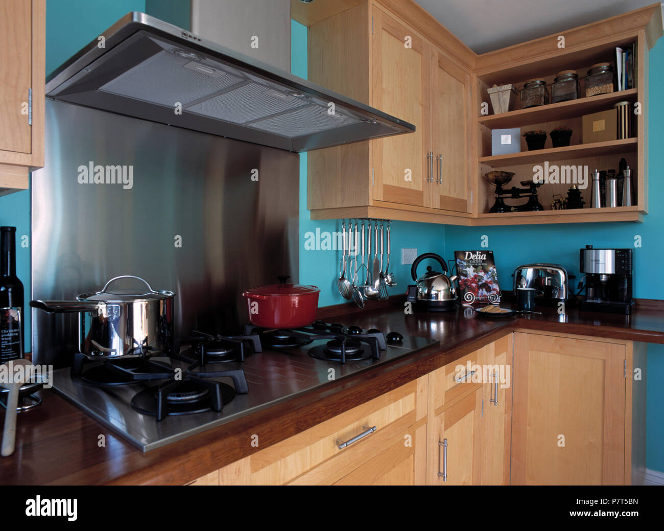 Stainless steel extractor fan above hob in blue kitchen with pale wood