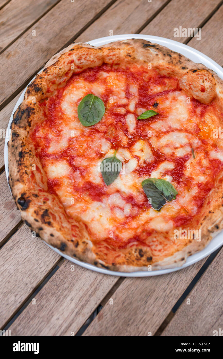 Original neapolitan pizza margherita on wooden table, served in Naples restaurant, Italy Stock Photo