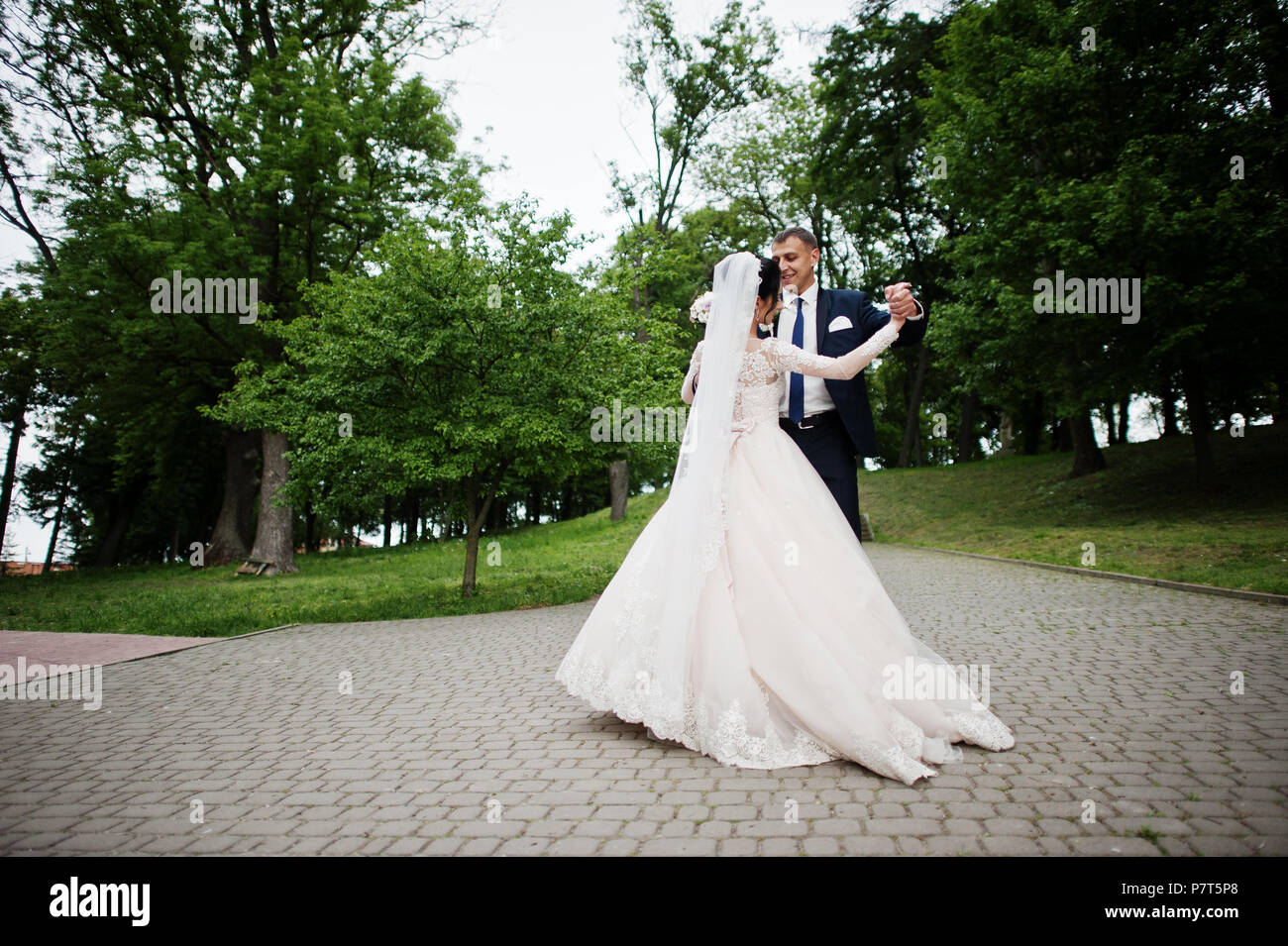 Romantic newly married couple dancing in the park on their wedding day ...