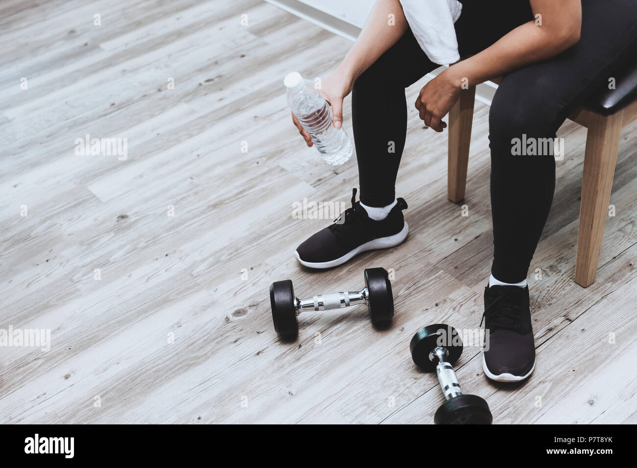 Fitness girl break for drinking water sitting with dumbbells weight training with copyspace Stock Photo