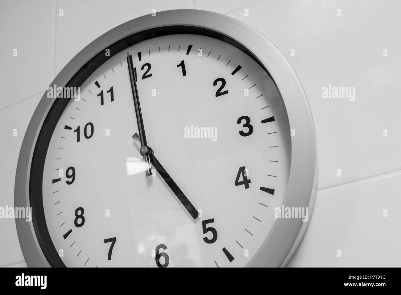 closeup simple clock on white wall time at 5 o'clock Stock Photo