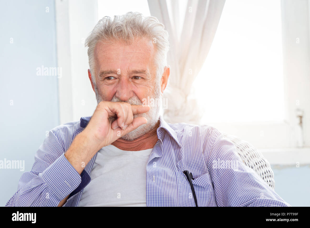 Elderly old man cute hiding smile look shy sitting in room with window. Stock Photo