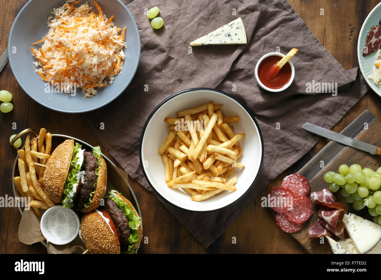 Top view dinner outdoor table with burger, french fries, salad and snacks  on wooden table Stock Photo - Alamy