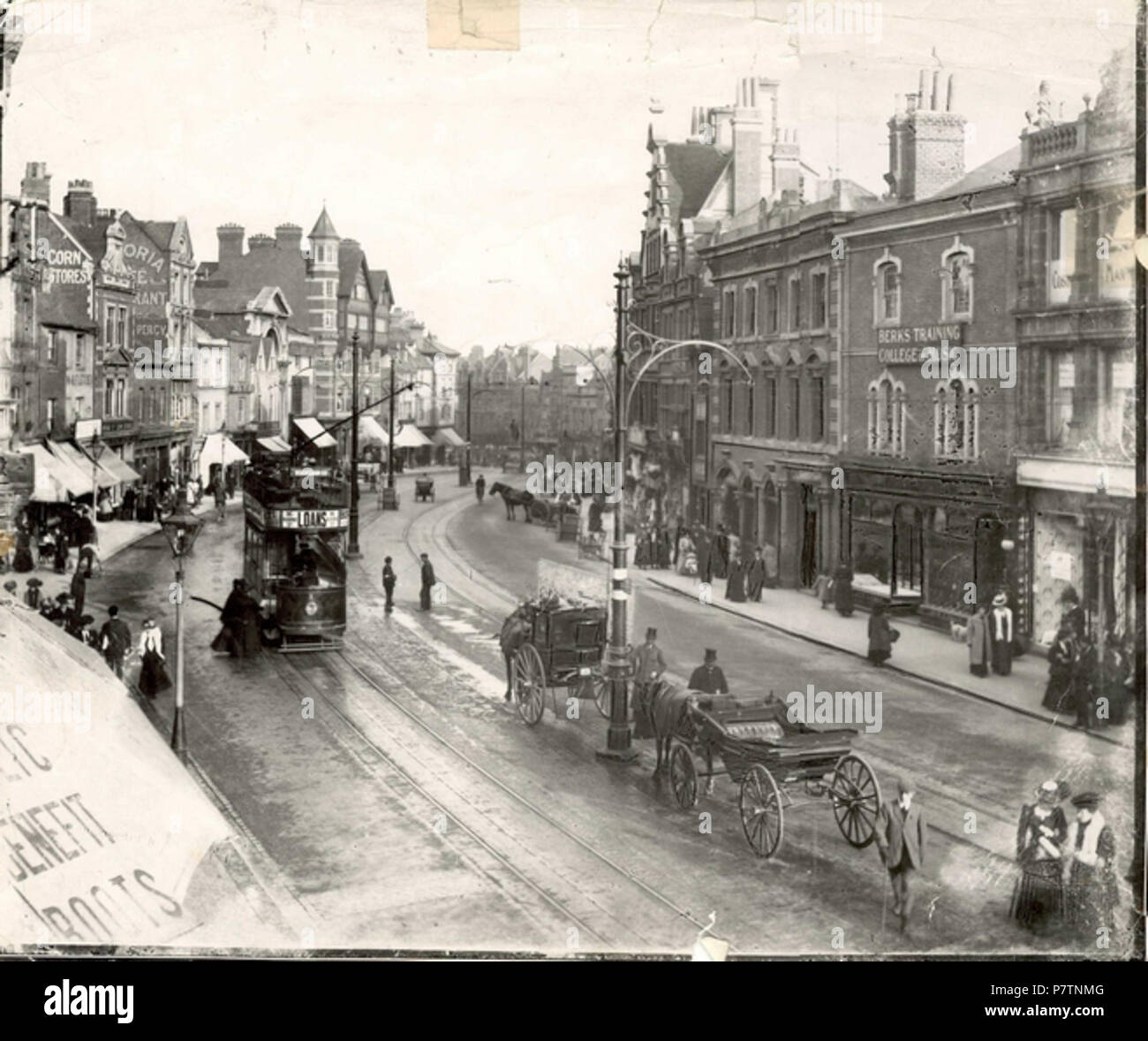 English: Broad Street, Reading, looking eastwards from an upper storey window, c. 1904. A tramcar heads eastwards, and two horse-drawn cabs wait in the middle of the road, by the trolley-pole. North side: No. 17 (W. and R. Fletcher, butchers); No. 14 (Royal Oak Inn); No. 6 (United Counties Bank). South side: Nos. 116 and 117 (Fergusons Ltd., Angel Brewery and Wine and Spirit Stores); Nos. 114 and 115 (Berkshire Training College of Music on the upper floors). 1900-1909. 1904 55 Broad Street, Reading, looking eastwards, c. 1904 Stock Photo