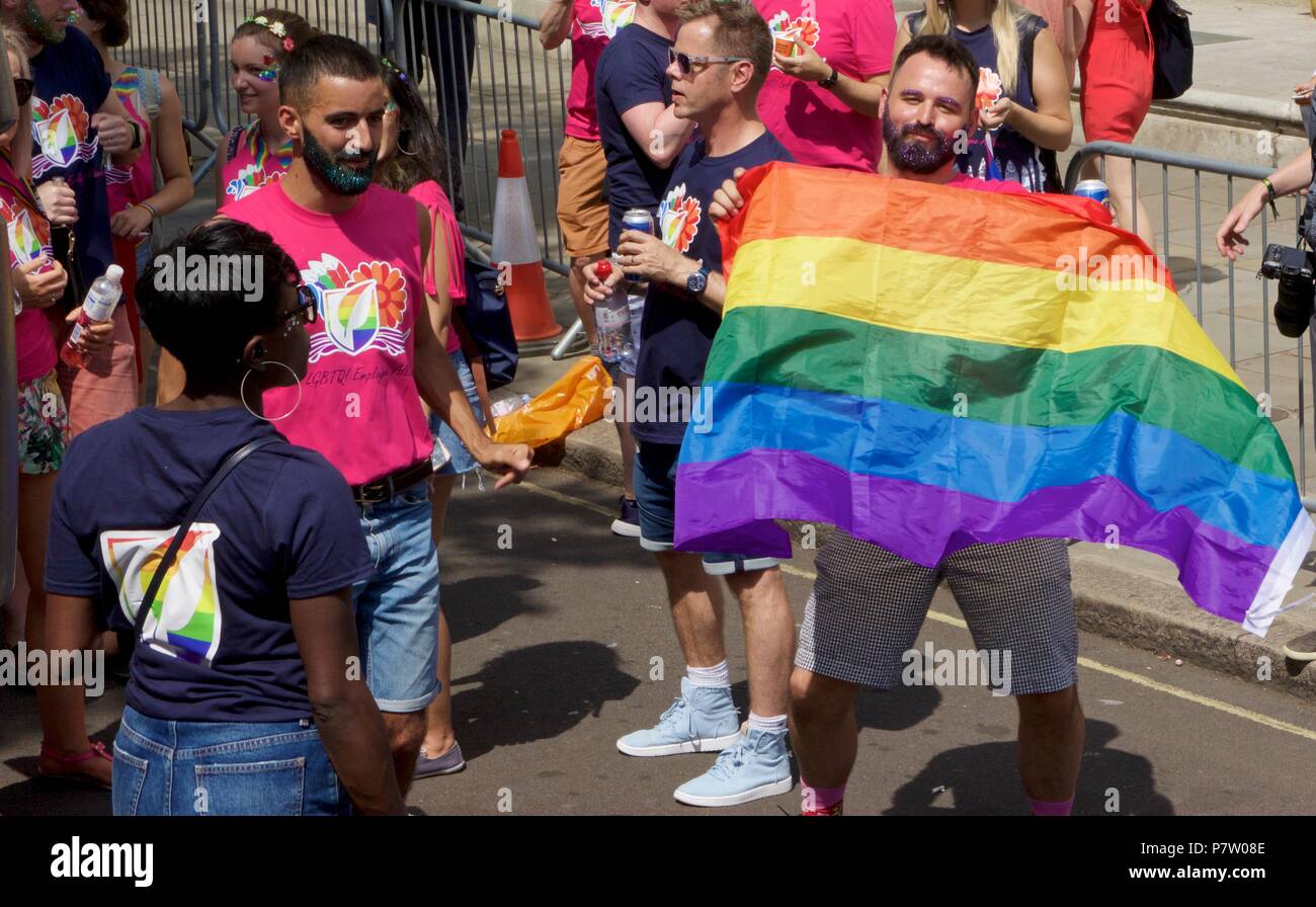 London, UK. 7th July 2018. Pride celebrations in London. A man holds a rainbow flag and looks at the camera. Credit: Dimple Patel/Alamy Live News Stock Photo